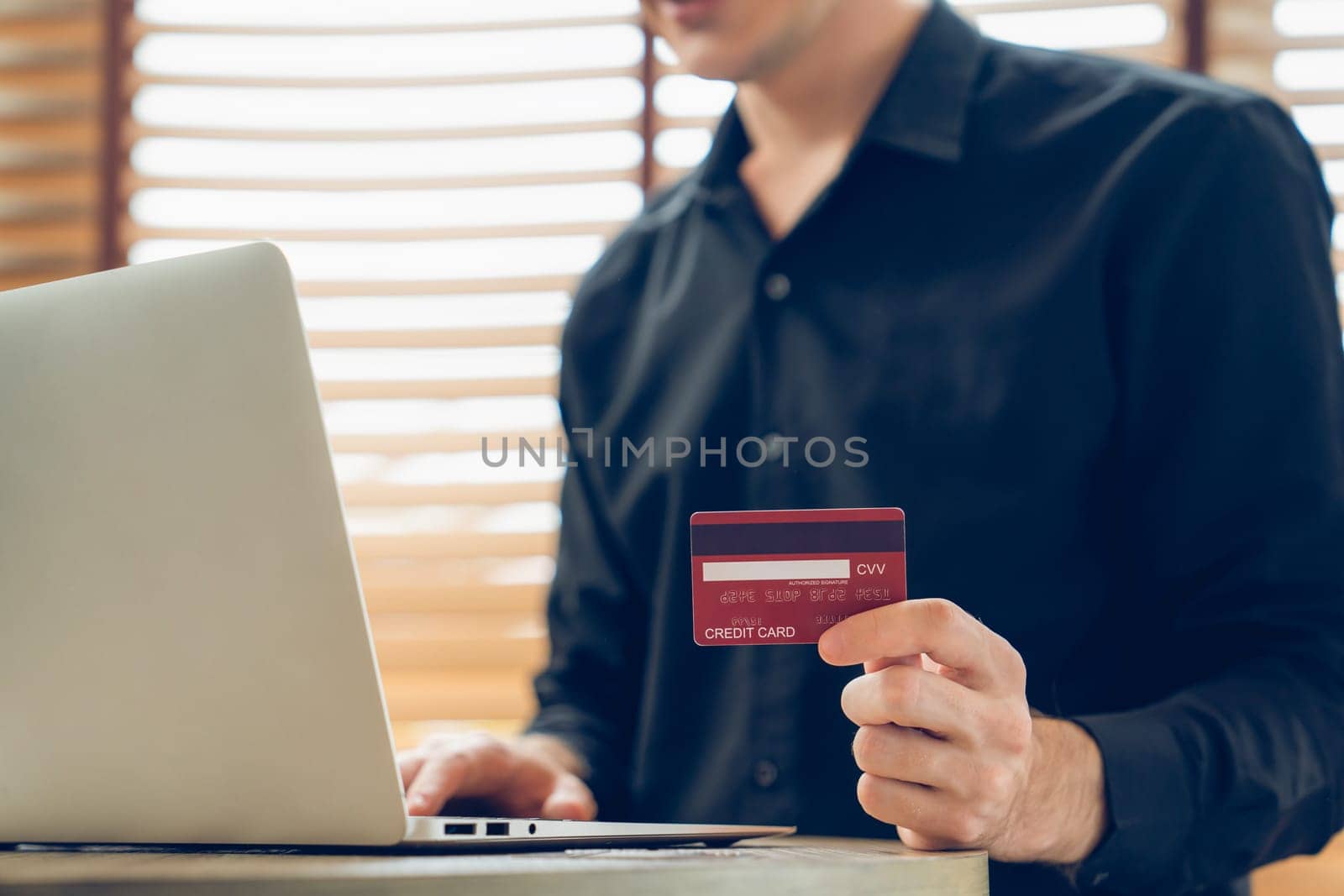 Young man using laptop with credit card for internet banking, online shopping E commerce by online payment gateway at home office. Modern and convenience online purchasing with debit card. Unveiling