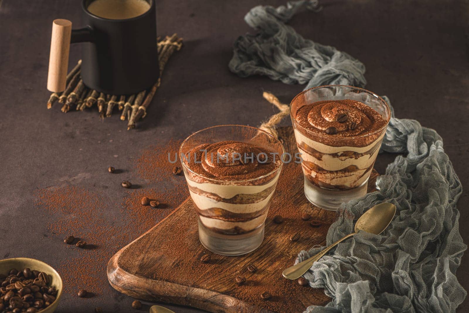 Delicious italian dessert tiramisu in a glasses on a dark slate, stone or concrete background.