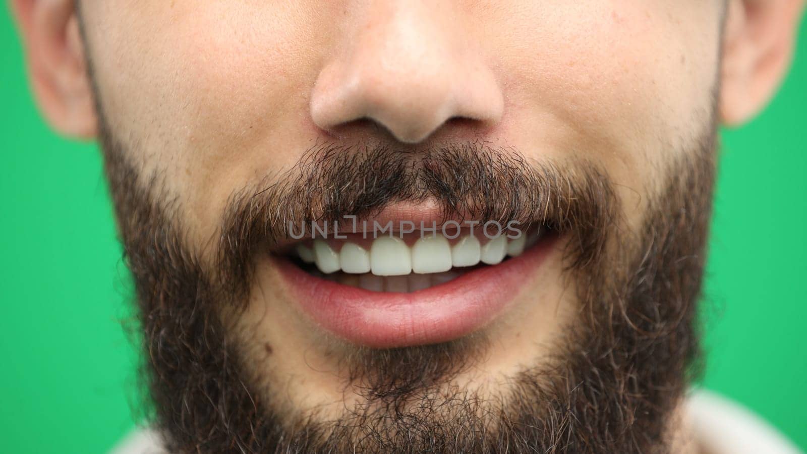 Man's mouth, close-up, on a green background.