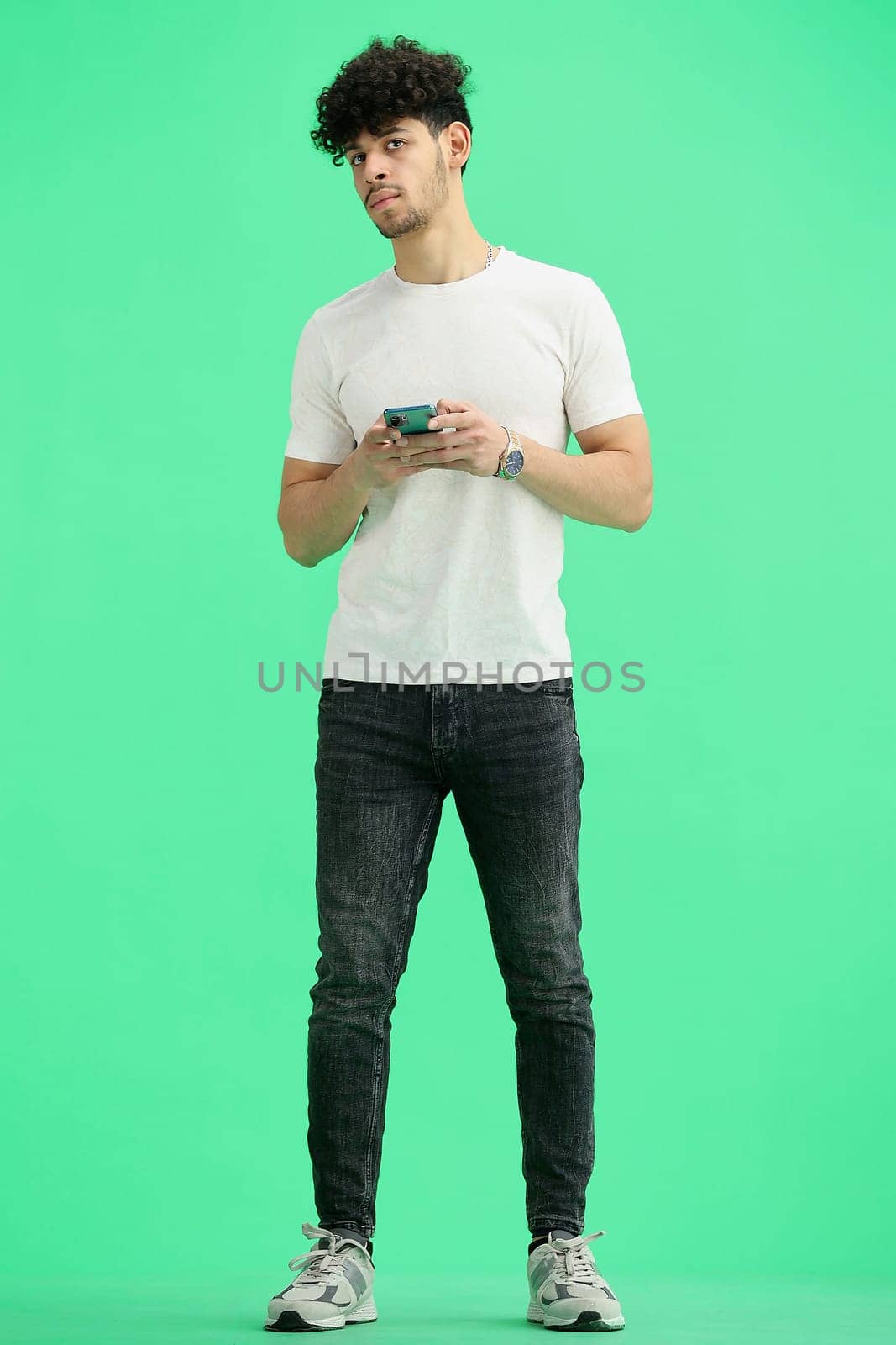 A man, on a green background, in full height, with a phone by Prosto