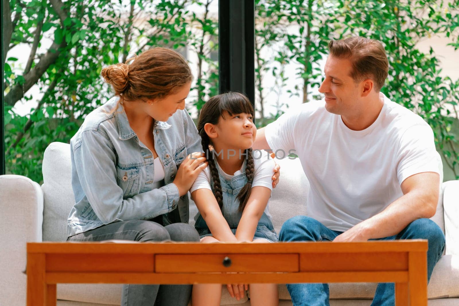 Parents comforting their daughter with loving hug, helping her feel secure and protected from fear, rest her head on shoulder. Happy family love and child care support concept. Synchronos