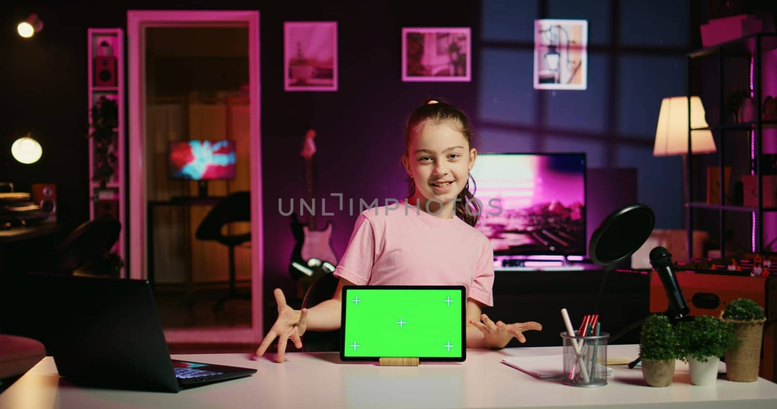 Smiling daughter filming online content with her parent using green screen tablet from sponsoring brand. Happy kid and her mother do internet videos for fans using chroma key device