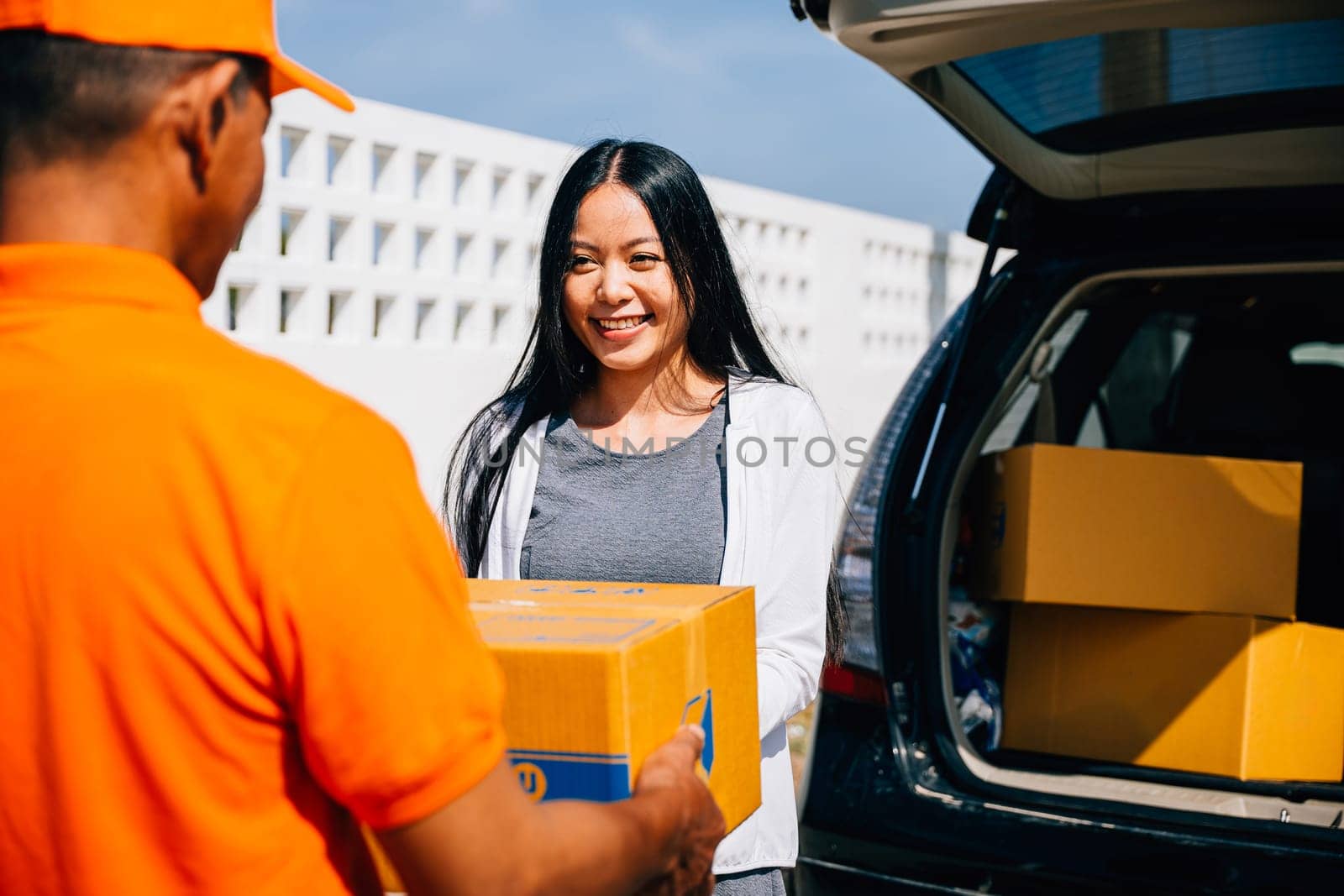 A smiling woman customer receives a cardboard parcel from a delivery service courier man at her home door showcasing efficient and modern home delivery logistics.