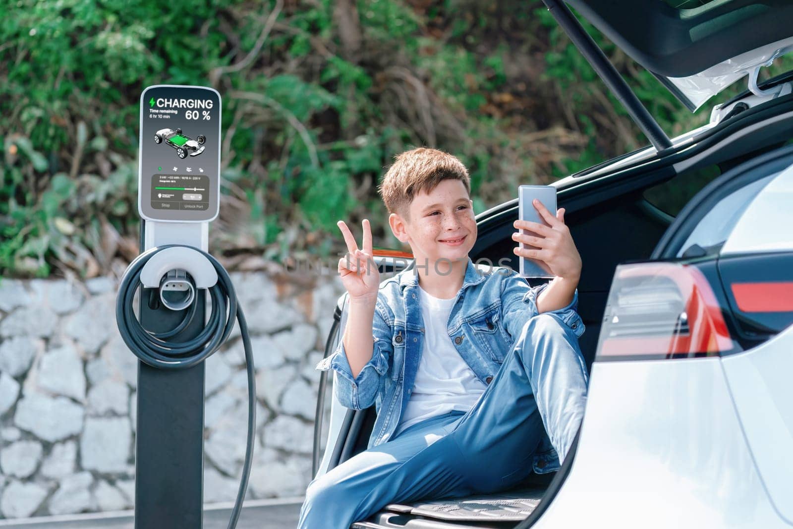 Little boy recharging electric car from EV charging station. Perpetual by biancoblue