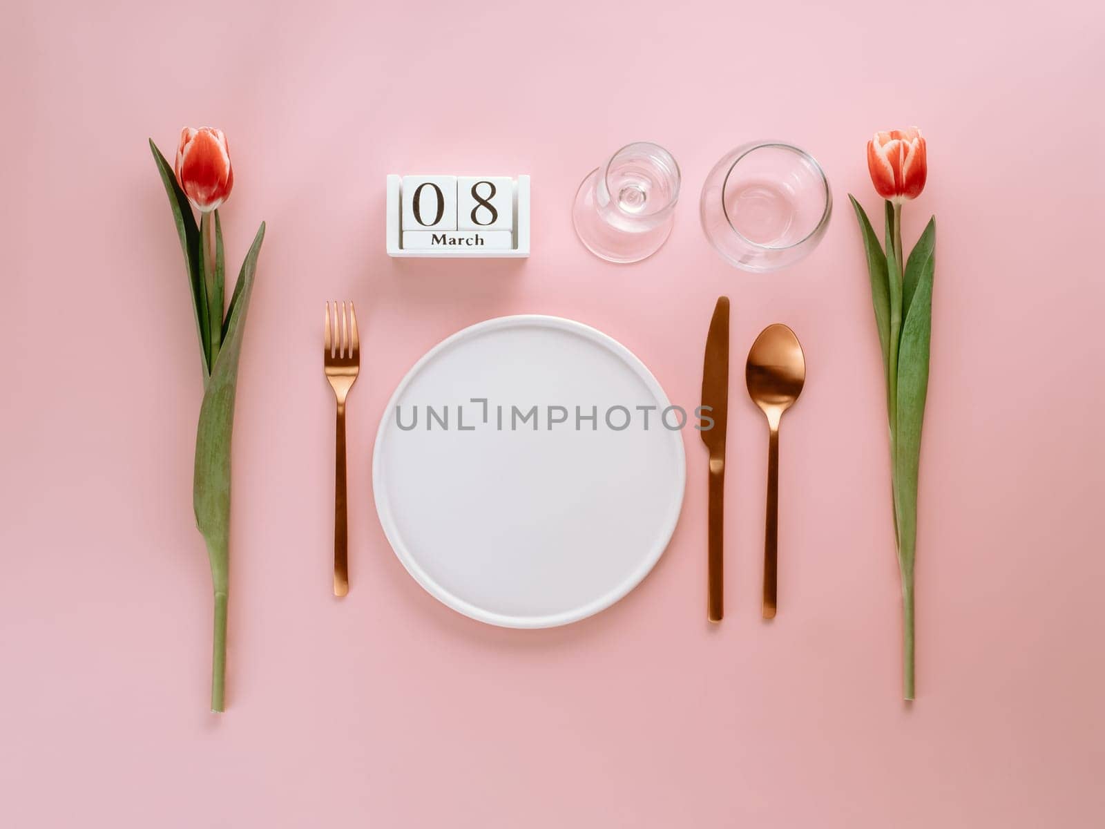 8 march table setting. Empty white plate, calendar with march eight date and red tulip on pink background. Aesthetic stylish dinner table setting for Women's day. Copy space. Flat lay