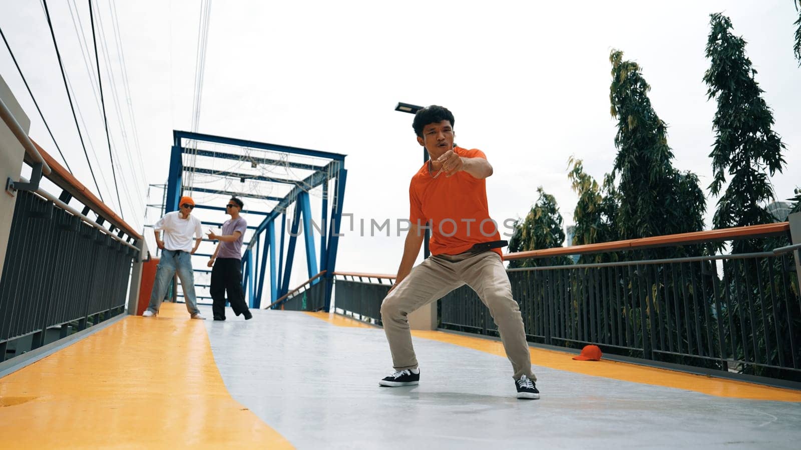 Skilled happy hipster perform footstep at bridge with low angle camera. Break dancer practice b-boy performance or freestyle dance while pose at camera. Modern lifestyle. Outdoor sport 2024. Sprightly
