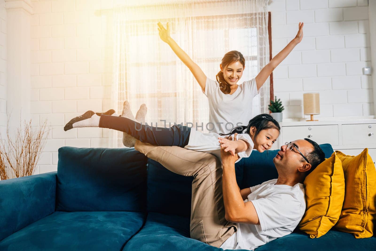 A family shares moments of joy and happiness during an airplane game in their cozy living room by Sorapop