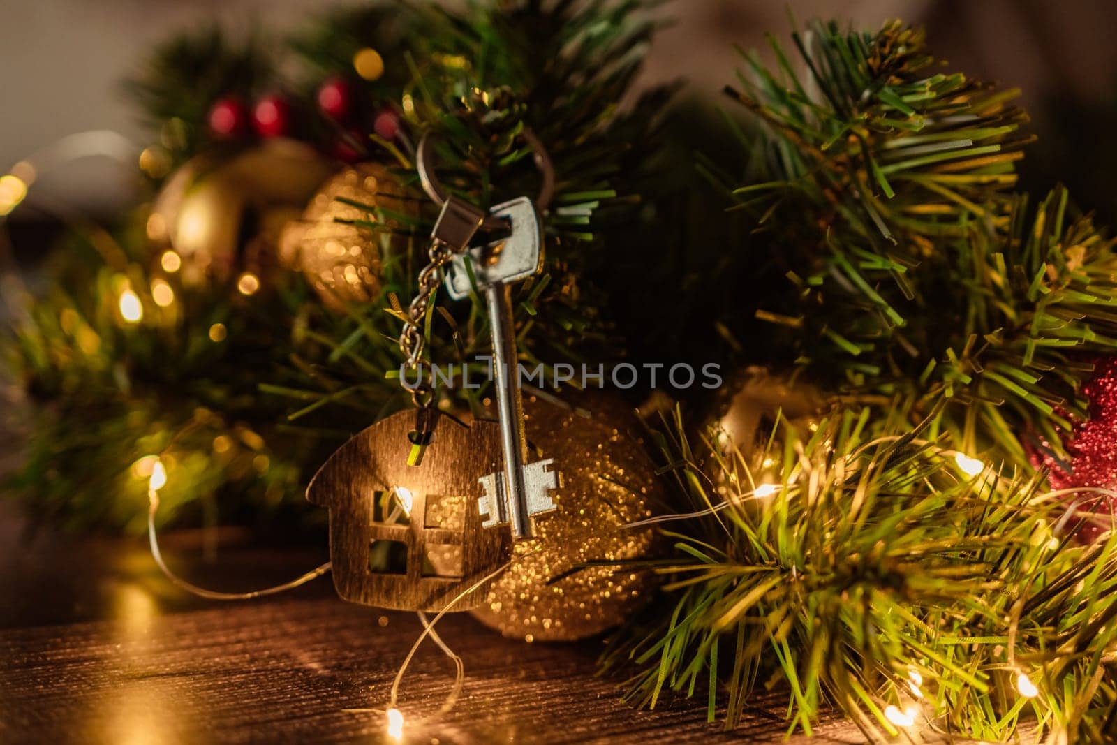 Gift key house with a keychain backdrop of Christmas tree. Building, design, project, moving to new house, mortgage, rent and purchase real estate. A gift for New Year, Christmas by Matiunina