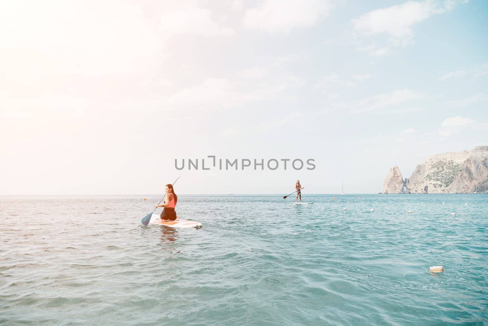Woman sup yoga. Happy young sporty woman practising yoga pilates on paddle sup surfboard. Female stretching doing workout on sea water. Modern individual female outdoor summer sport activity