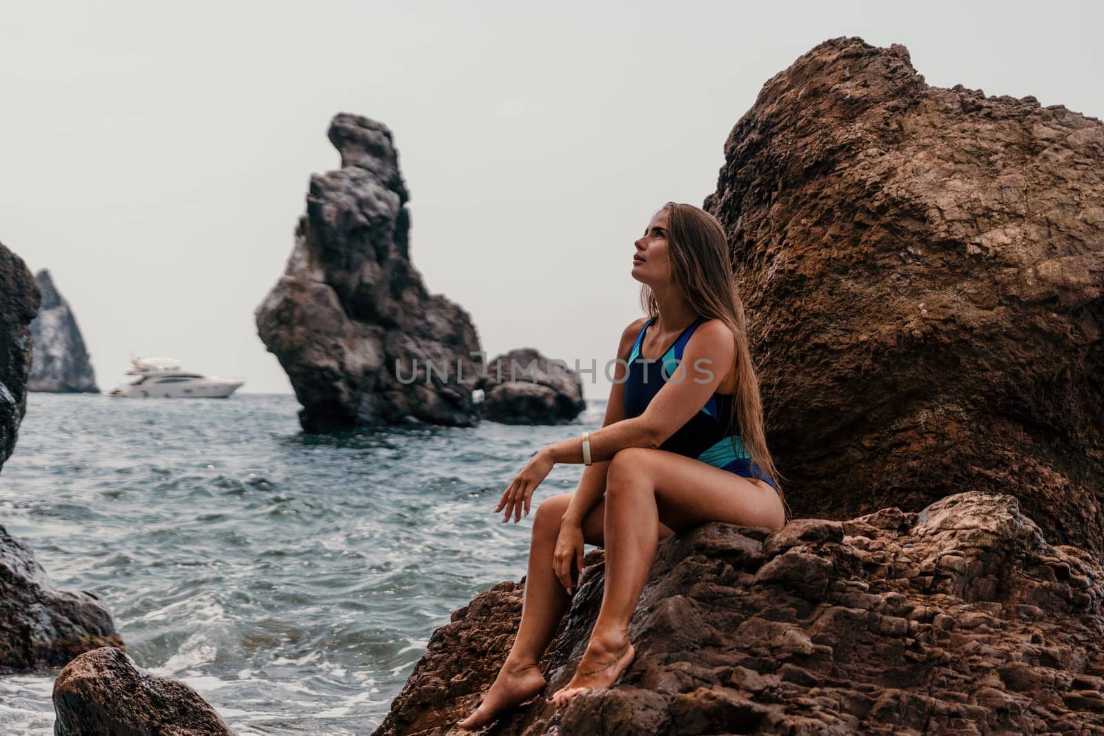 Woman travel sea. Young Happy woman in a long red dress posing on a beach near the sea on background of volcanic rocks, like in Iceland, sharing travel adventure journey