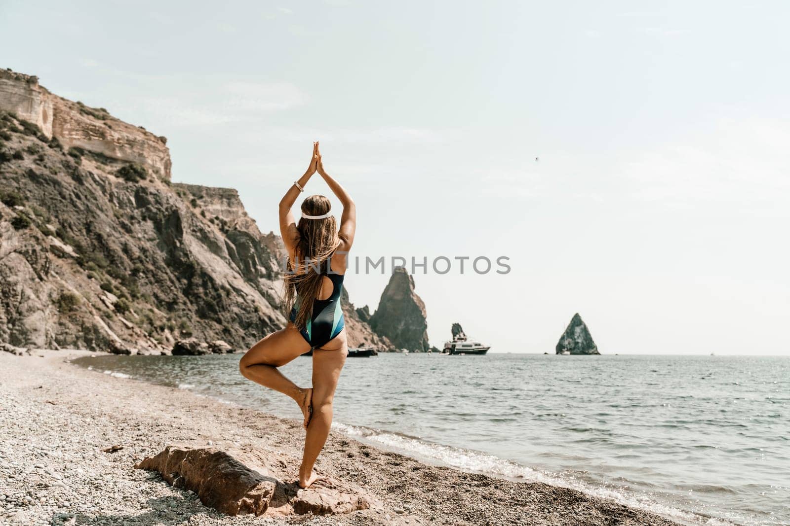 Woman beach vacation photo. A happy tourist in a blue bikini enjoying the scenic view of the sea and volcanic mountains while taking pictures to capture the memories of her travel adventure