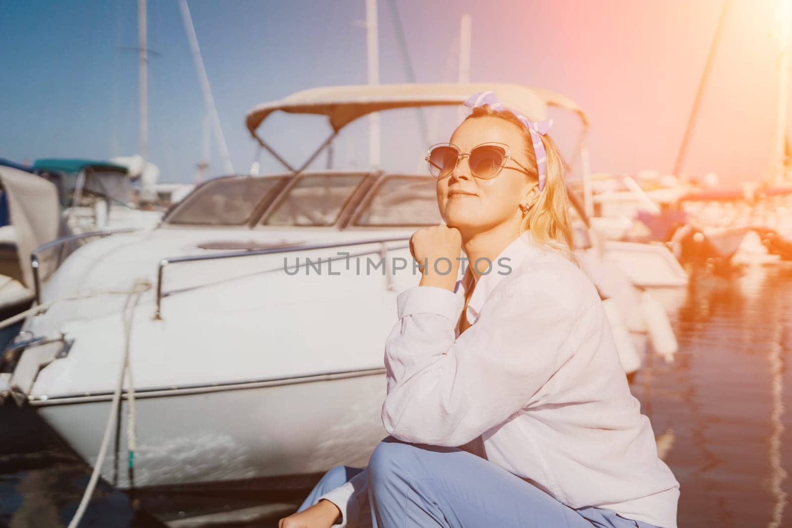 Woman in white shirt in marina , surrounded by several other boats. The marina is filled with boats of various sizes, creating a lively and picturesque atmosphere