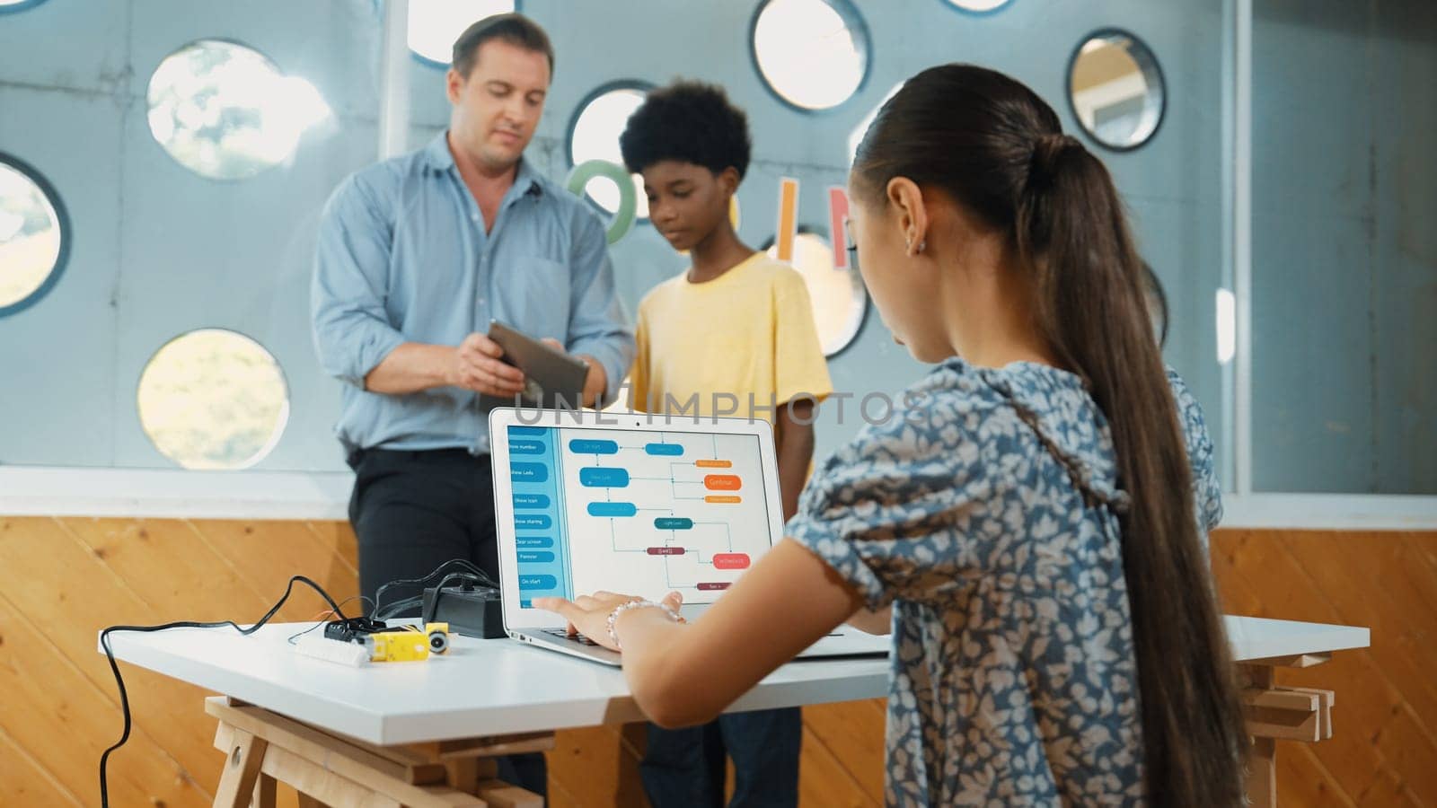 Highschool girl writing prompt while boy looking at teacher tablet. Cute academic student learning about coding and programing system. while happy teacher giving advice and comment pupil. Edification.