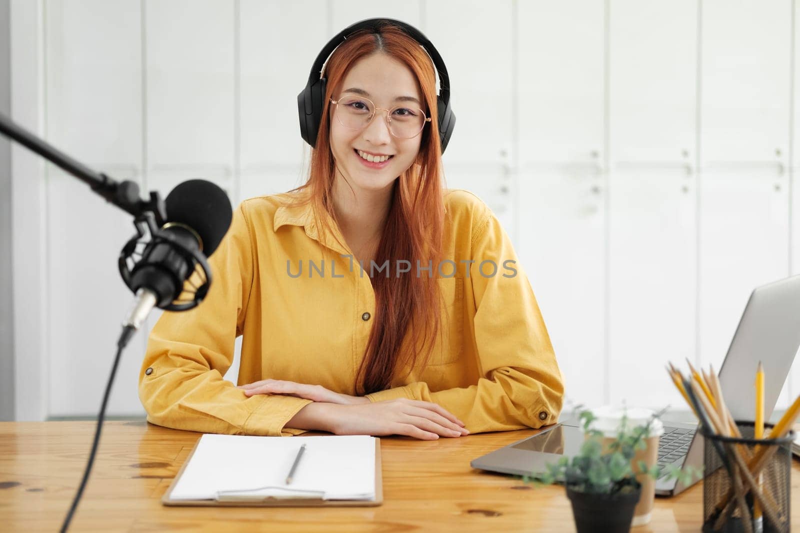 Female podcaster making audio podcast from her home studio by ijeab