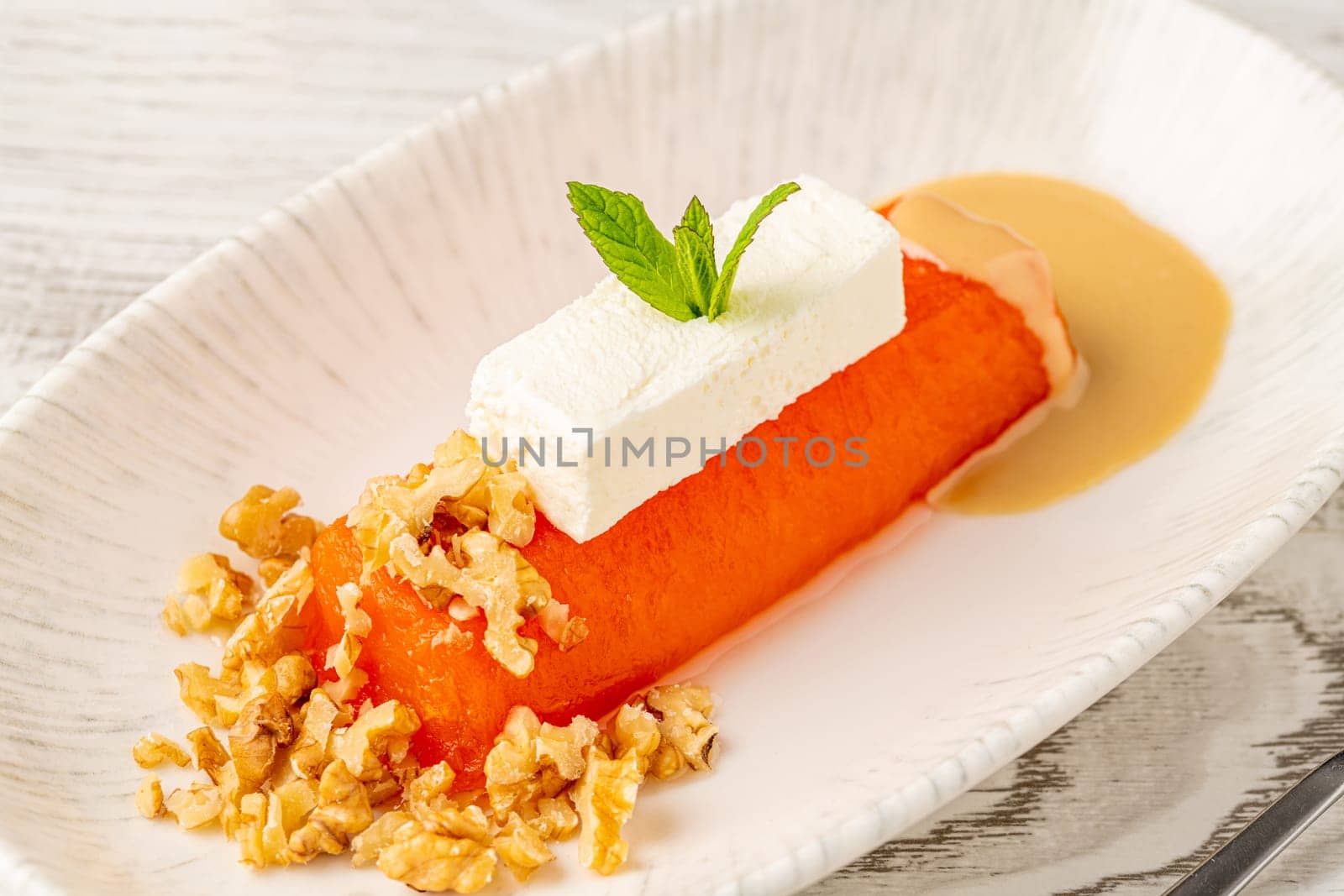 Pumpkin dessert with tahini and walnuts on a white porcelain plate by Sonat