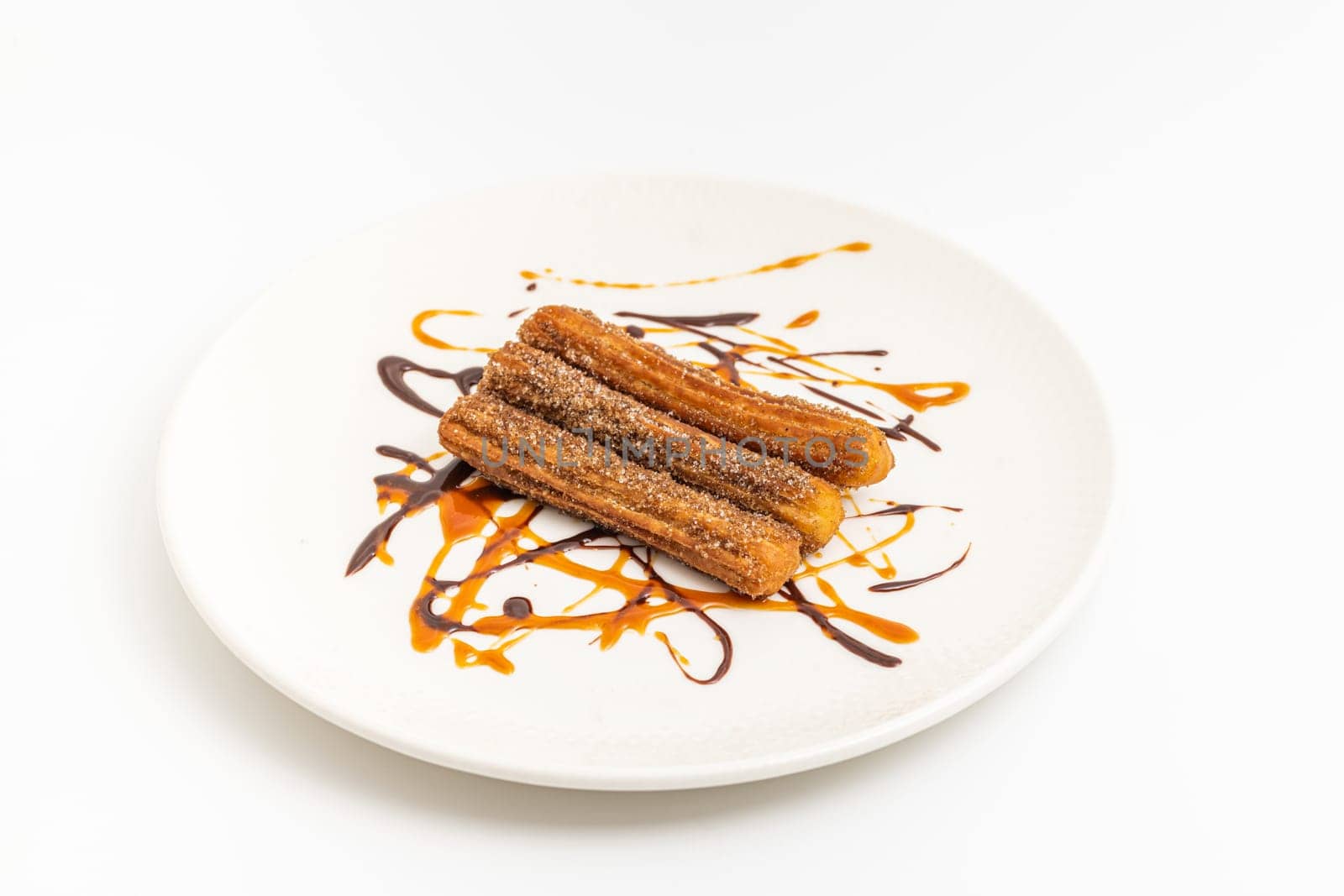 Hot churros with chocolate sauce on white background.