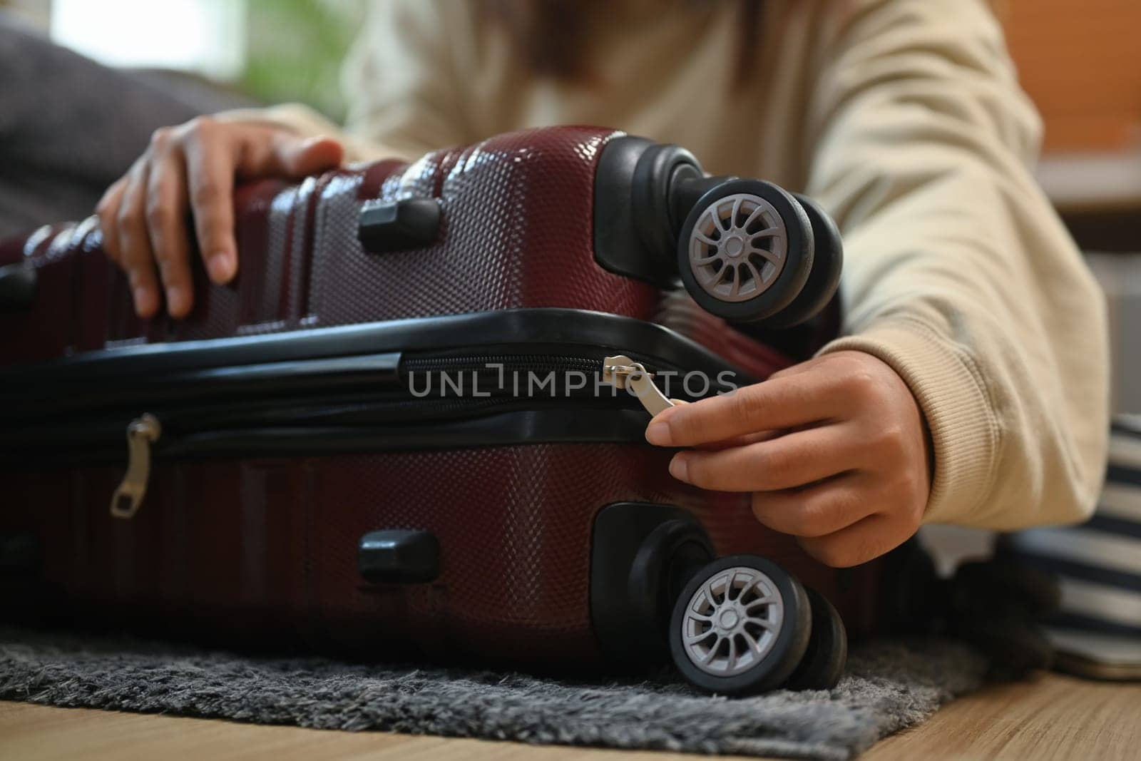 Closeup woman getting ready to travel vacation, packing suitcase for trip on floor in living room.