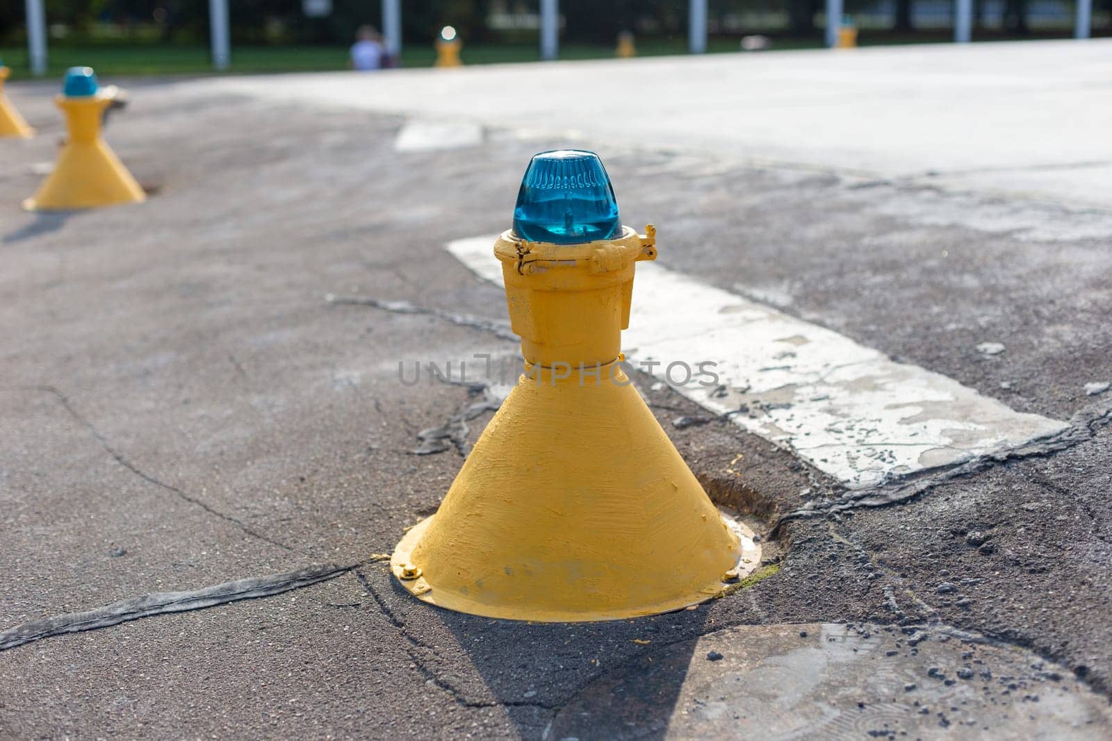 Close-up of a yellow runway marker with a blue light, indicating directions on the airport tarmac by Zakharova