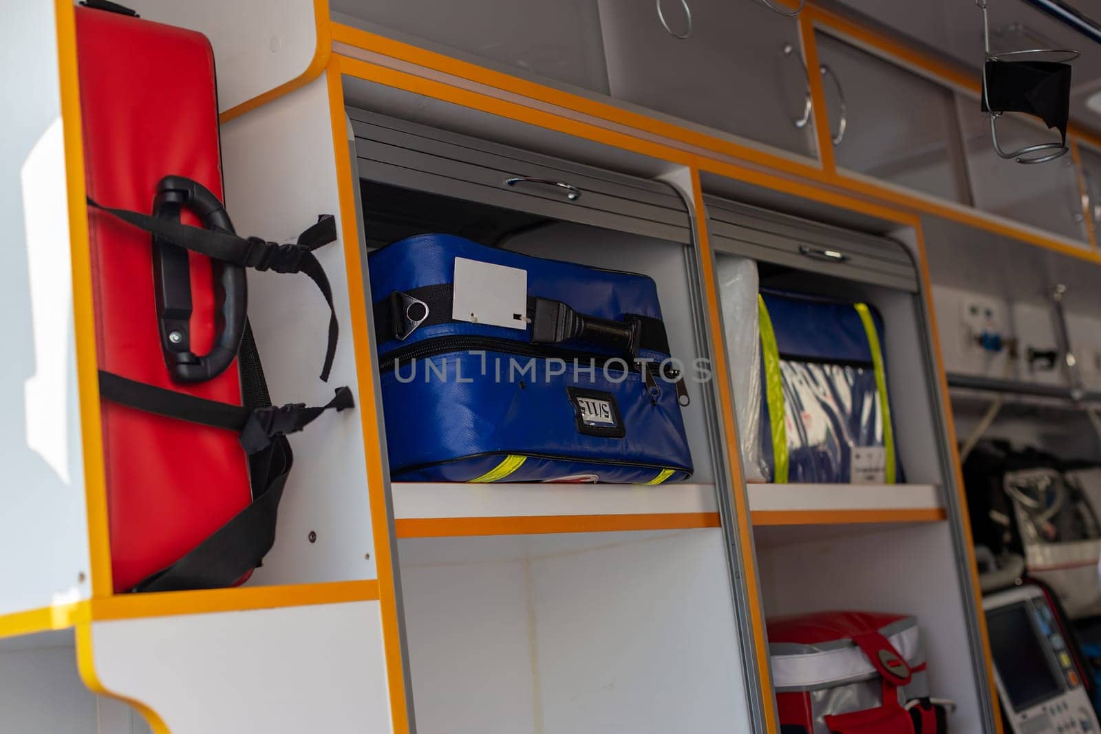 Inside the ambulance, medical supplies and storage compartments are visible, with red and blue bags.