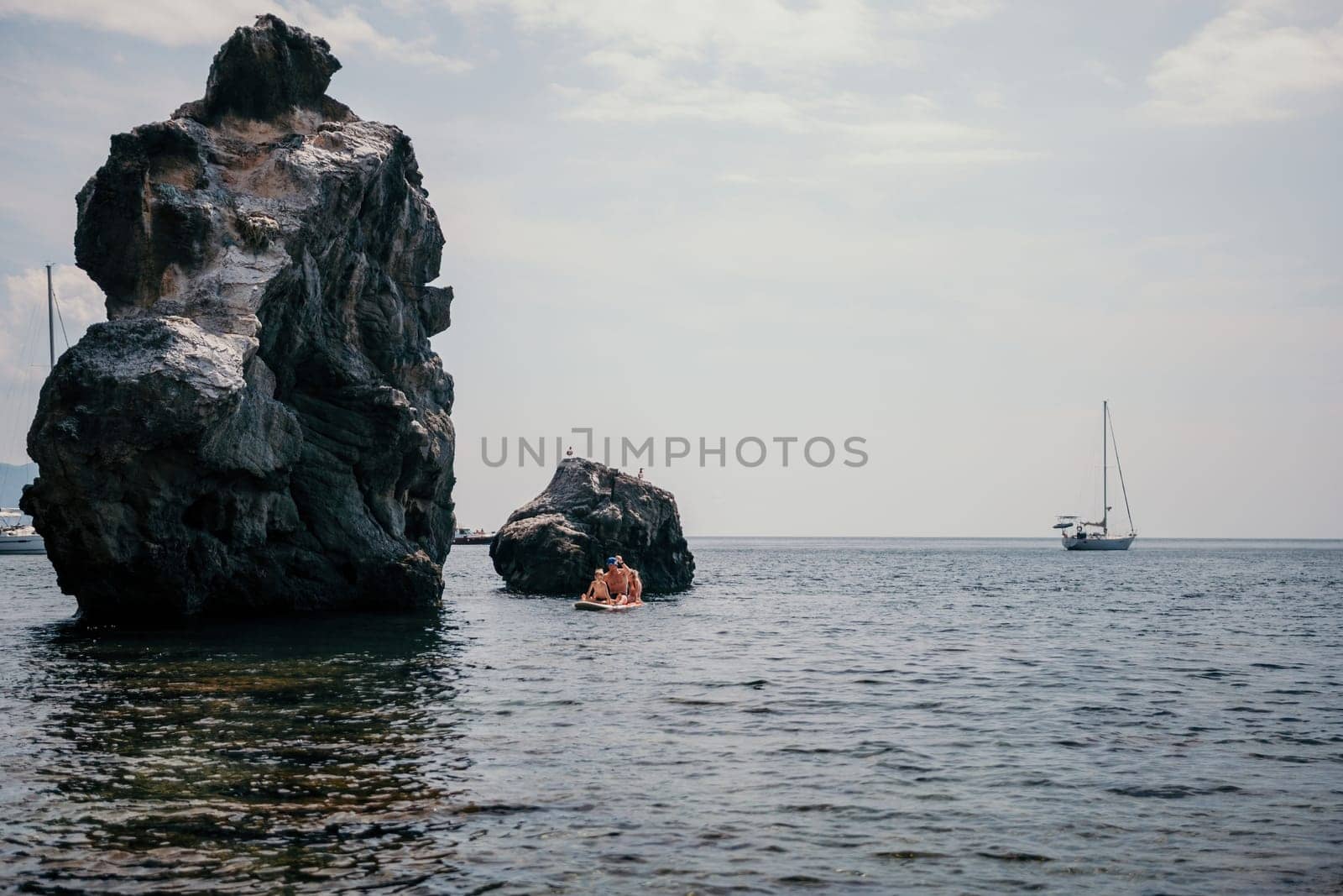 Family sea sup. Young happy father with his son and daughter Floating on a SUP board, paddling in blue sea water. summer vacation and Dad and Son Daughter concept. by panophotograph
