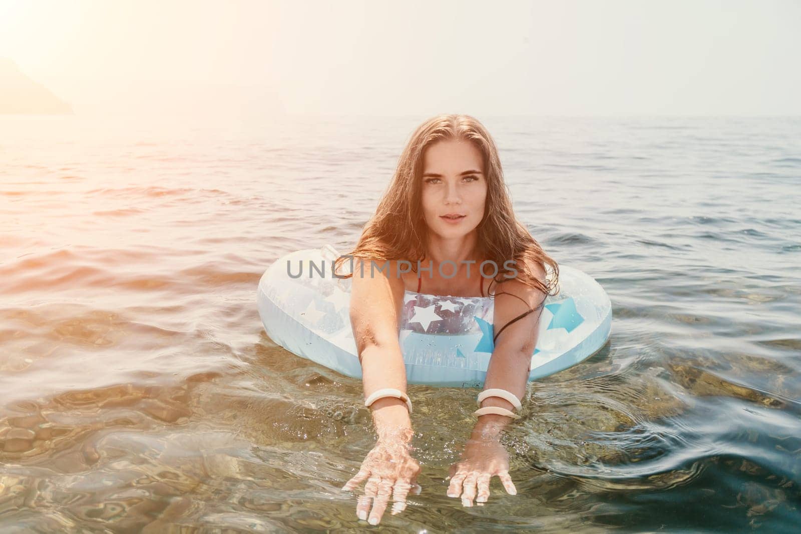 Woman summer sea. Happy woman swimming with inflatable donut on the beach in summer sunny day, surrounded by volcanic mountains. Summer vacation concept. by panophotograph