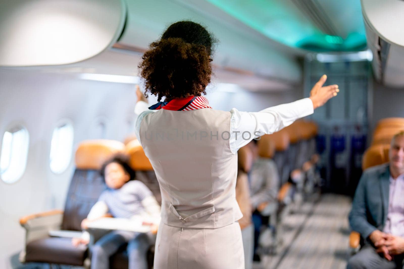 Air hostess or airline staff woman demostrate and guide the emergency exit of airplane to the passenger before take of the flight to the other city.