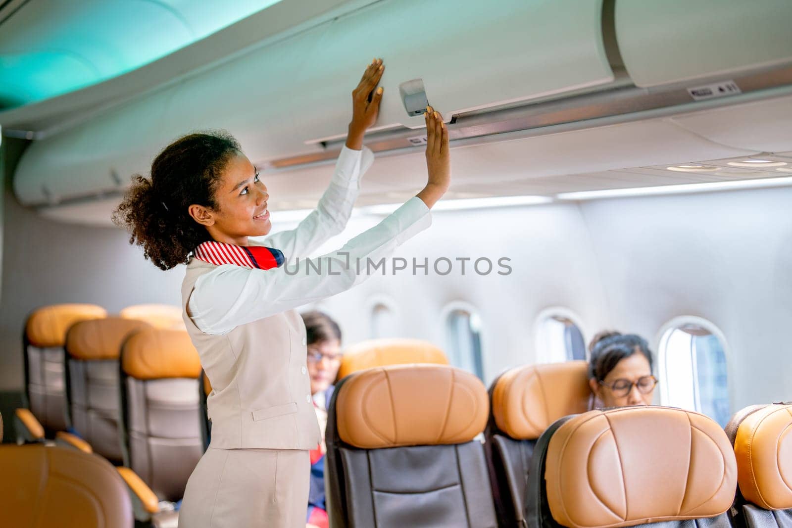 Close up view air hostess walk to close luggage compartment of airplane before take off and bring the passenger to the destination with happiness. by nrradmin