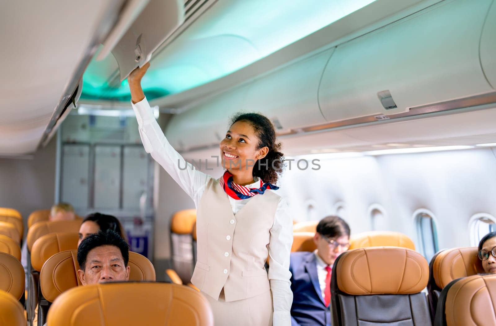 Wide shot of air hostess walk to close luggage compartment of airplane before take off and bring the passenger to the destination with happiness.