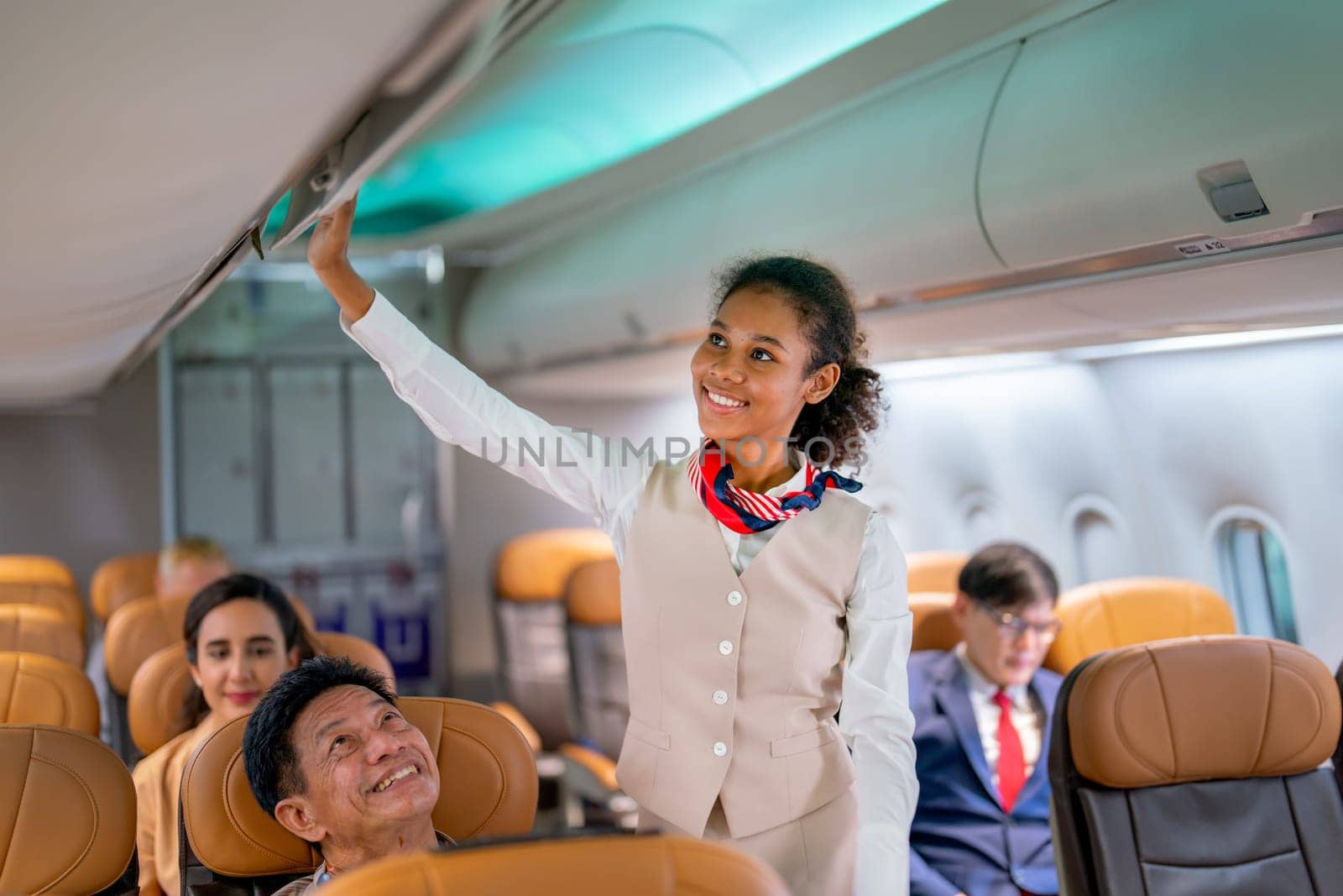 Close up view air hostess or airline staff walk to close luggage compartment of airplane before take off and bring the passenger to the destination with happiness. by nrradmin