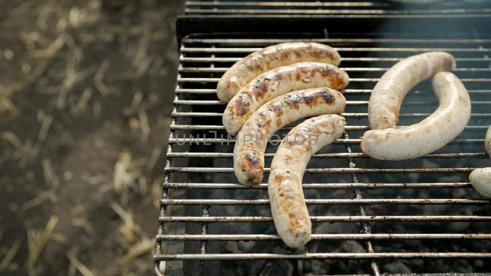 Bratwurst or Hot Dogs on Grill with Flames. Sausages are fried on a barbecue grill. by Rusrussid