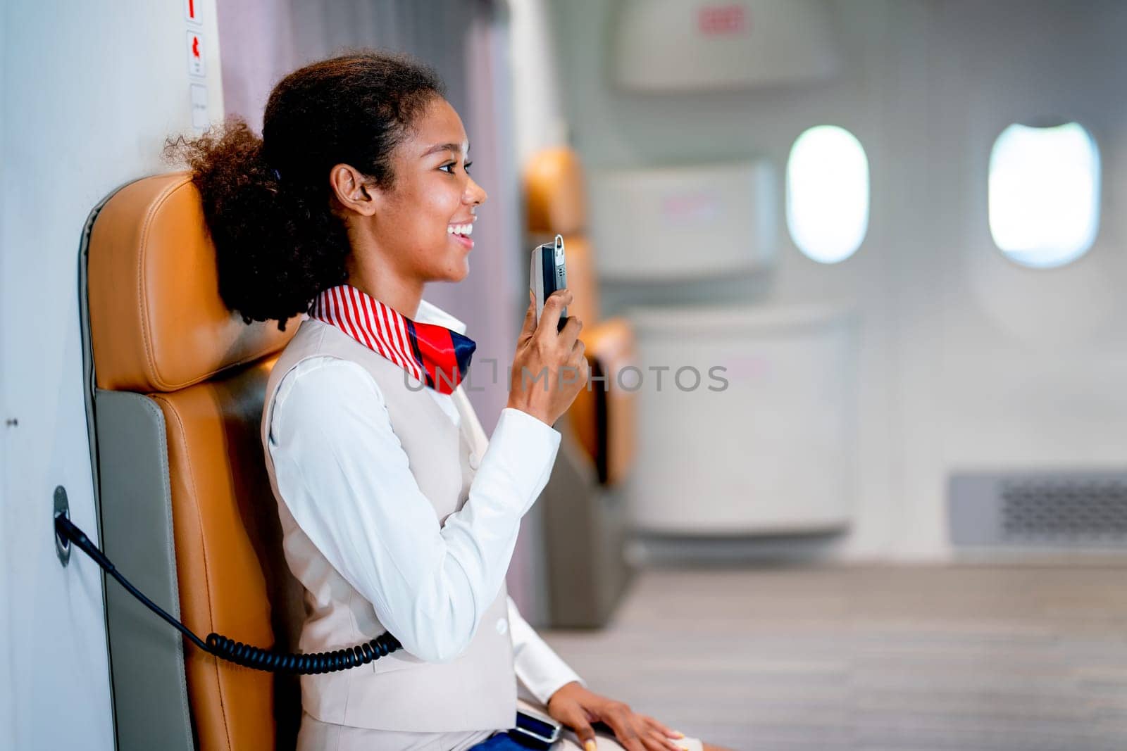 Air hostess or airline staff sit on cabin crew seat and use microphone of airplane to give by nrradmin