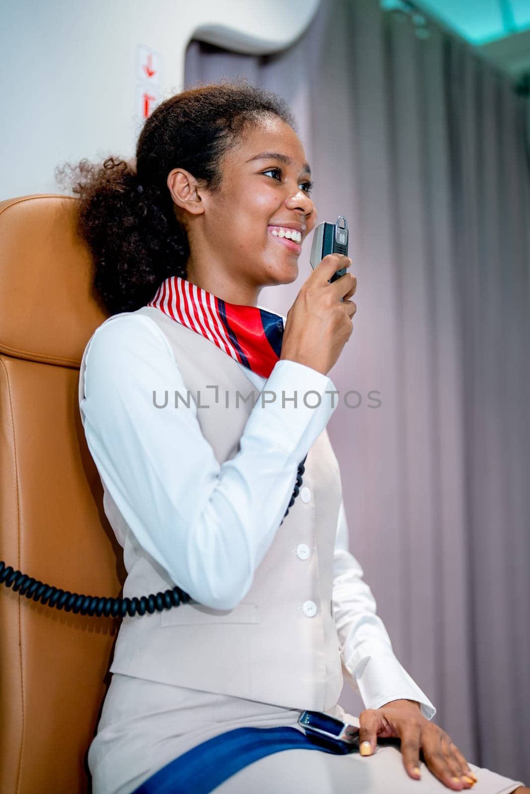 Air hostess or airline staff sit on cabin crew seat and use microphone of airplane to give