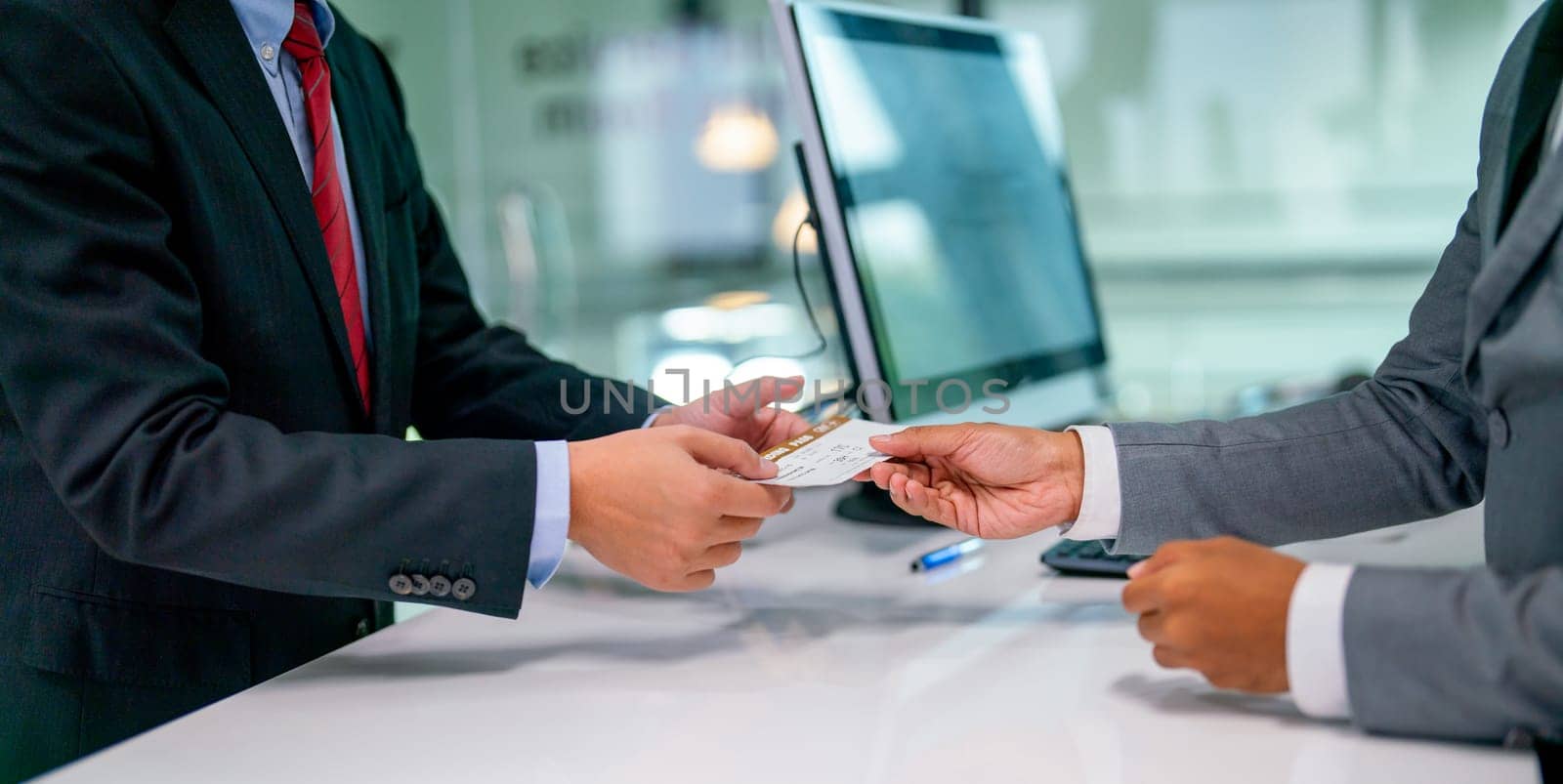 Close up hands of airline staff give boarding pass for flight to the customer at service counter in the airport.