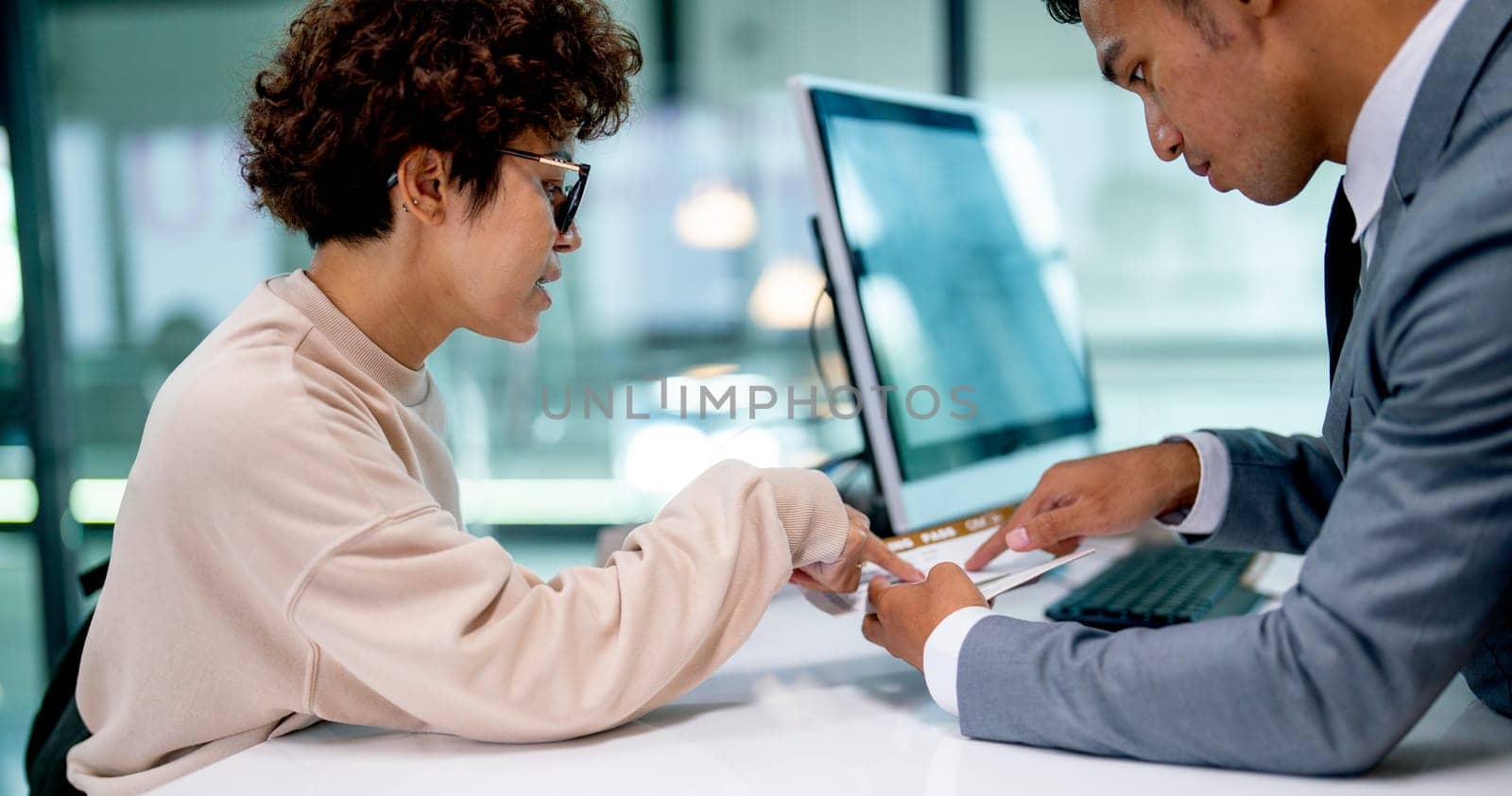 Airline staff give boarding pass to the passenger Asian woman and explain about the detail at counter service in the airport.