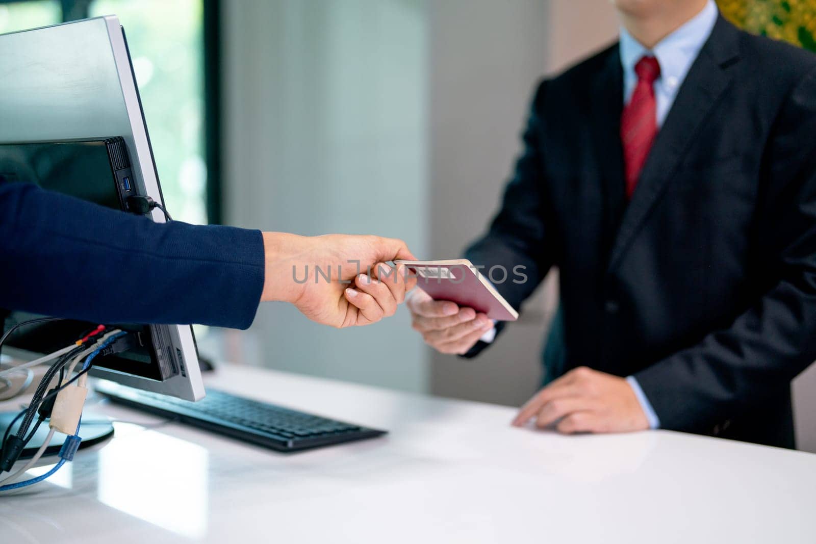 Close up hands of the customer give passport book to airline staff for flight at service counter in the airport. by nrradmin