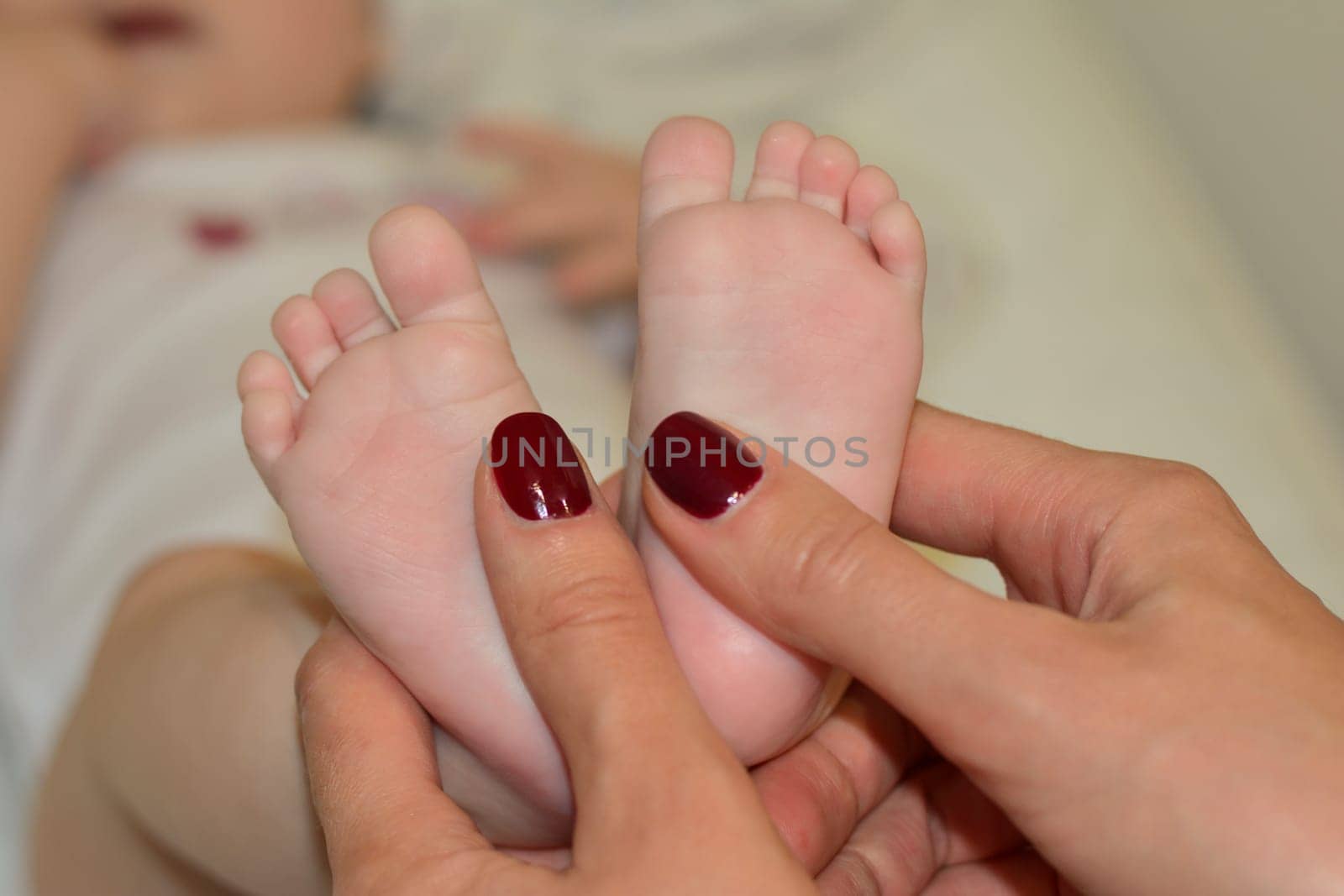 Mother makes massage on the foot of baby with oil