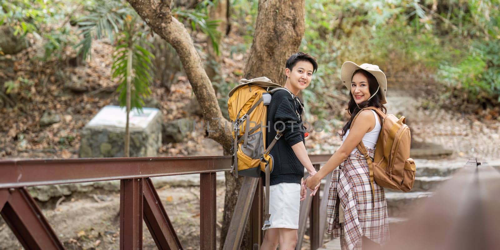 Lovely couple lesbian woman with backpack hiking in nature. Loving LGBT romantic moment in mountains by nateemee