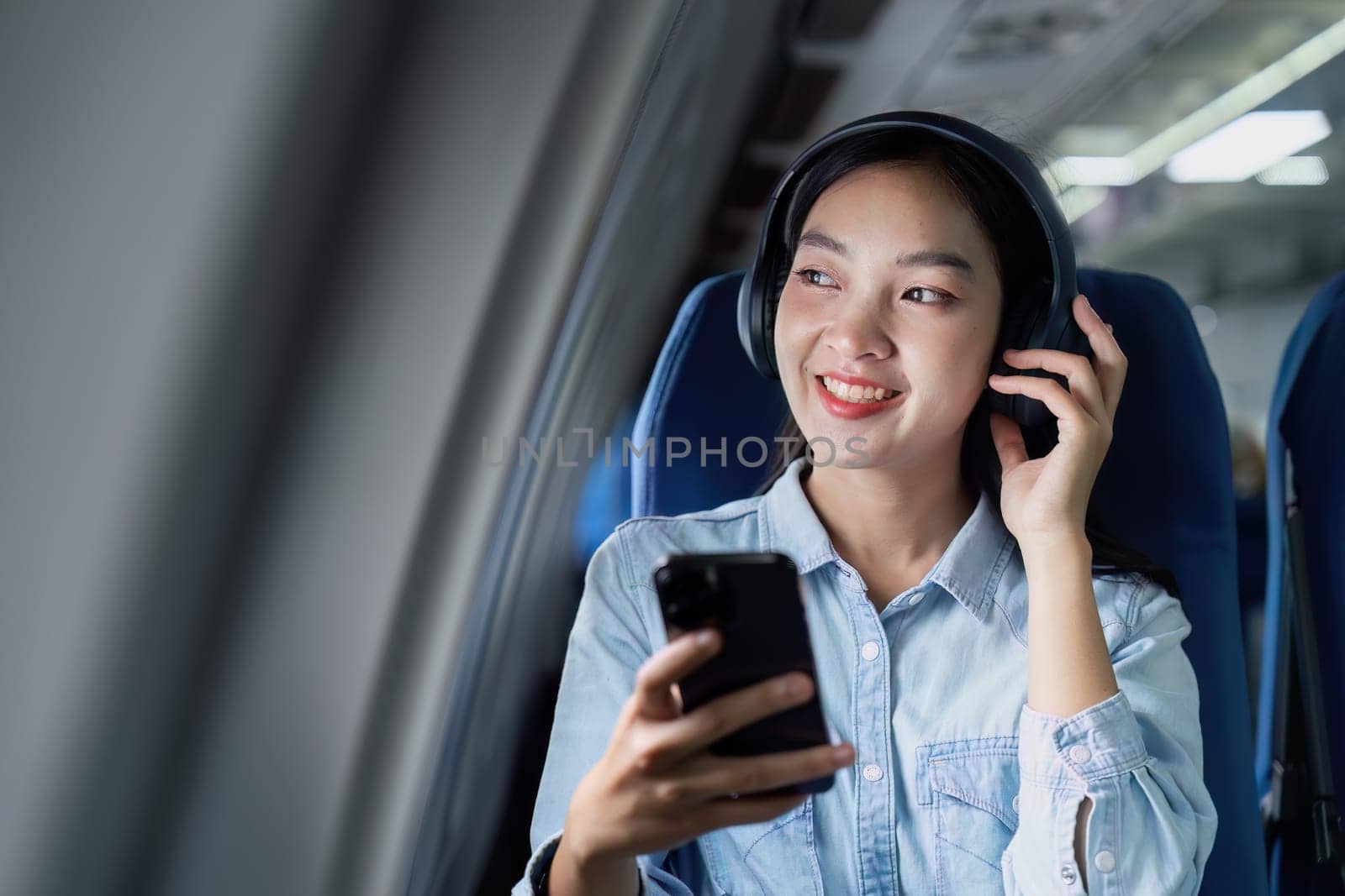 Asian people female person onboard, airplane window, using mobile while on the plane by itchaznong