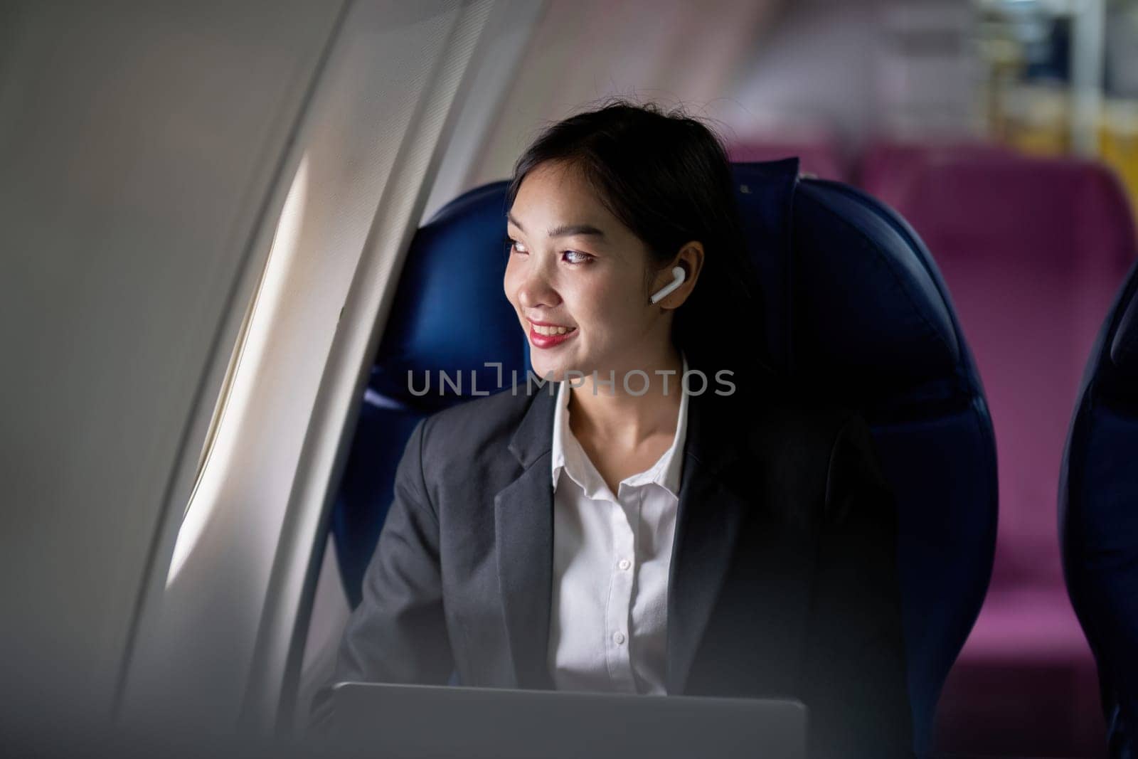 Successful young asian business woman sits in airplane cabin plane and working from anywhere. Flying at first class by nateemee