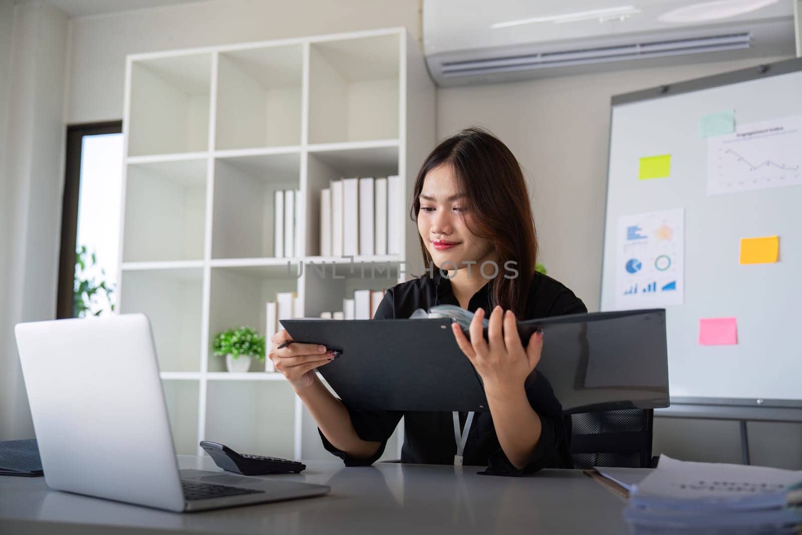 Entrepreneur or business woman working comparing documents with a computer laptop sitting in a desk at office.