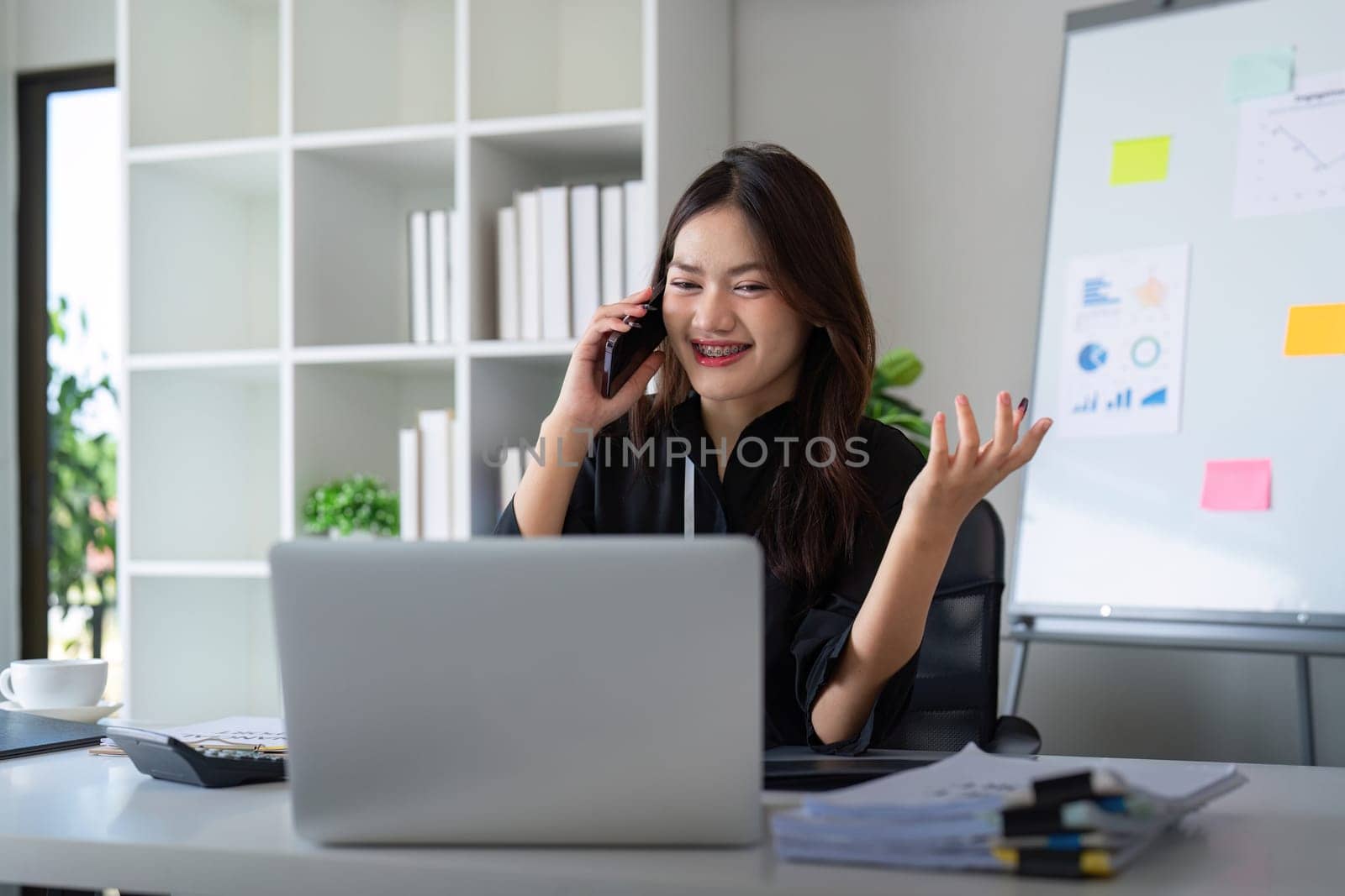 Happy confident businesswoman talking on the phone. Smiling female business person talking work using talking on the phone at office sitting at desk by nateemee