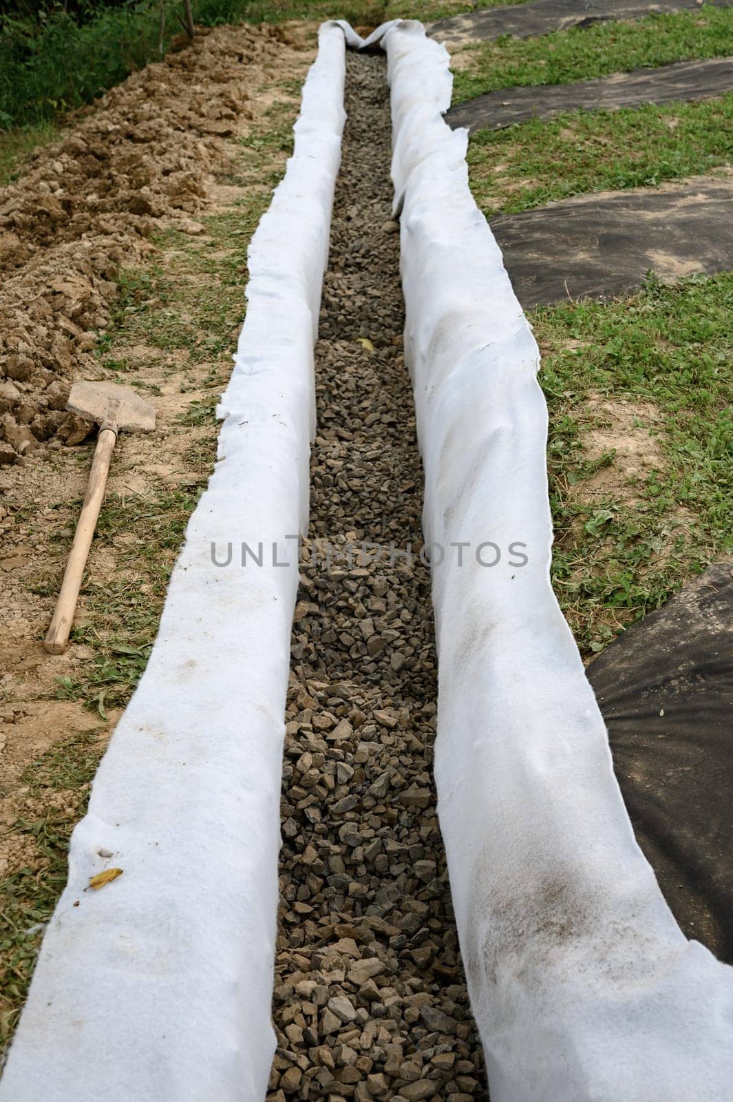 The drainage trench is covered with geotextile and filled with crushed stone to drain ground water from the site and adjacent territory