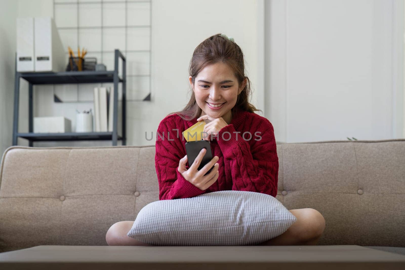 Young Asian woman hands holding credit card and using smartphone for internet purchase. Online shopping, Online payment at home.
