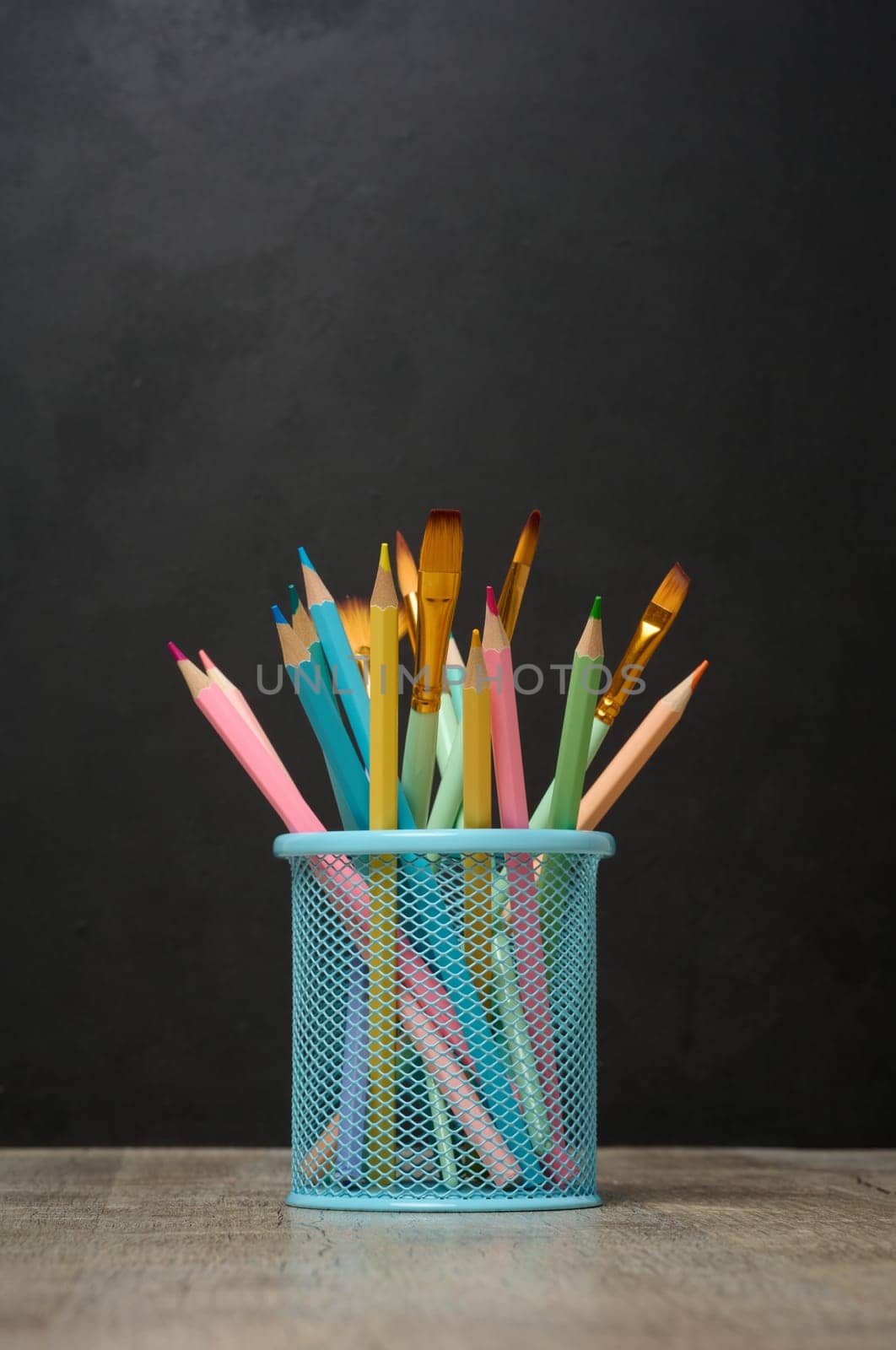 Multi-colored wooden pencils on a black chalk board background