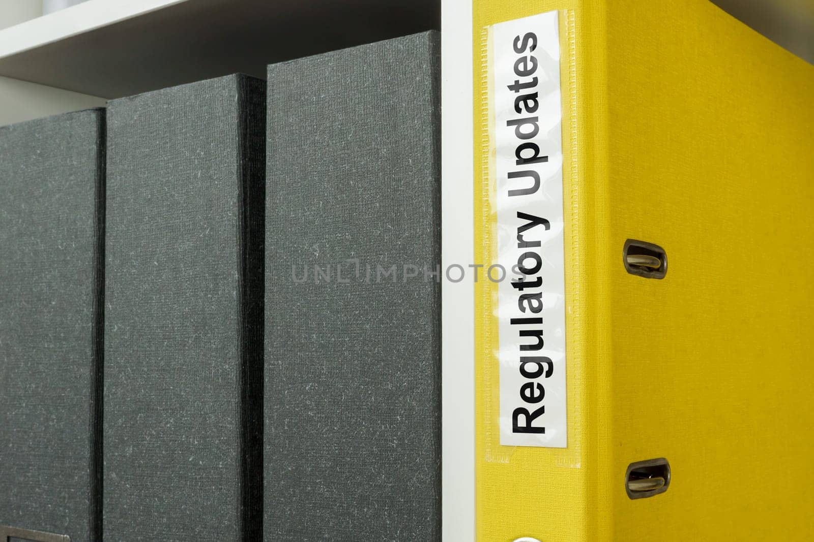 Yellow folder with label regulatory updates on the shelf.