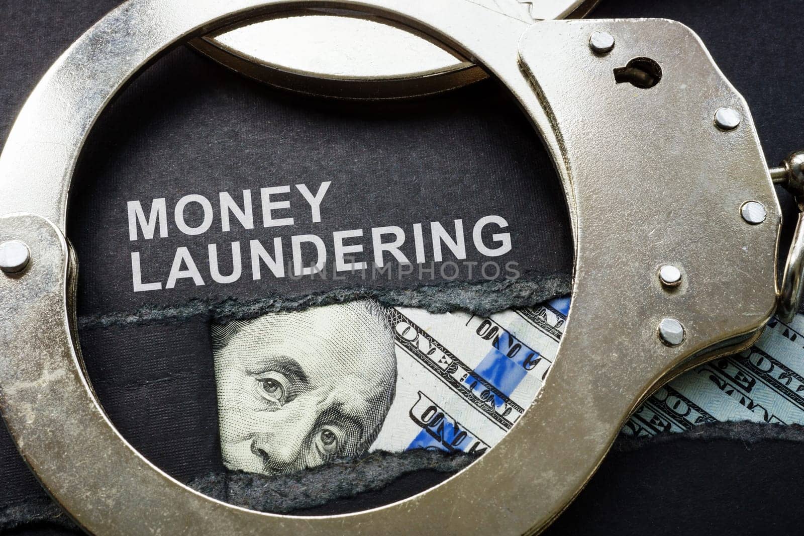 Torn paper, handcuffs and money. Money laundering concept. by designer491