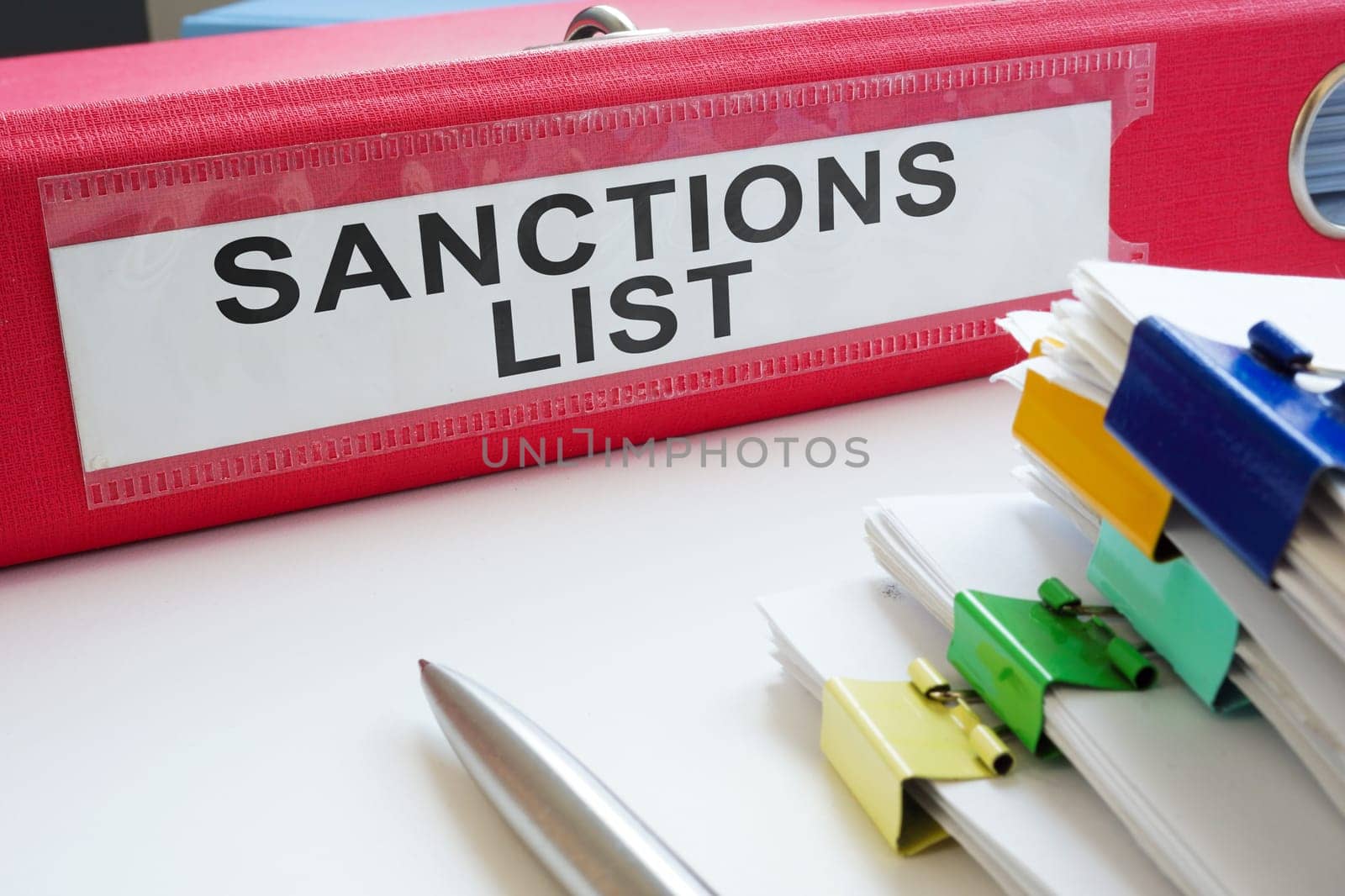 Folder with a label sanctions list and stack of documents.