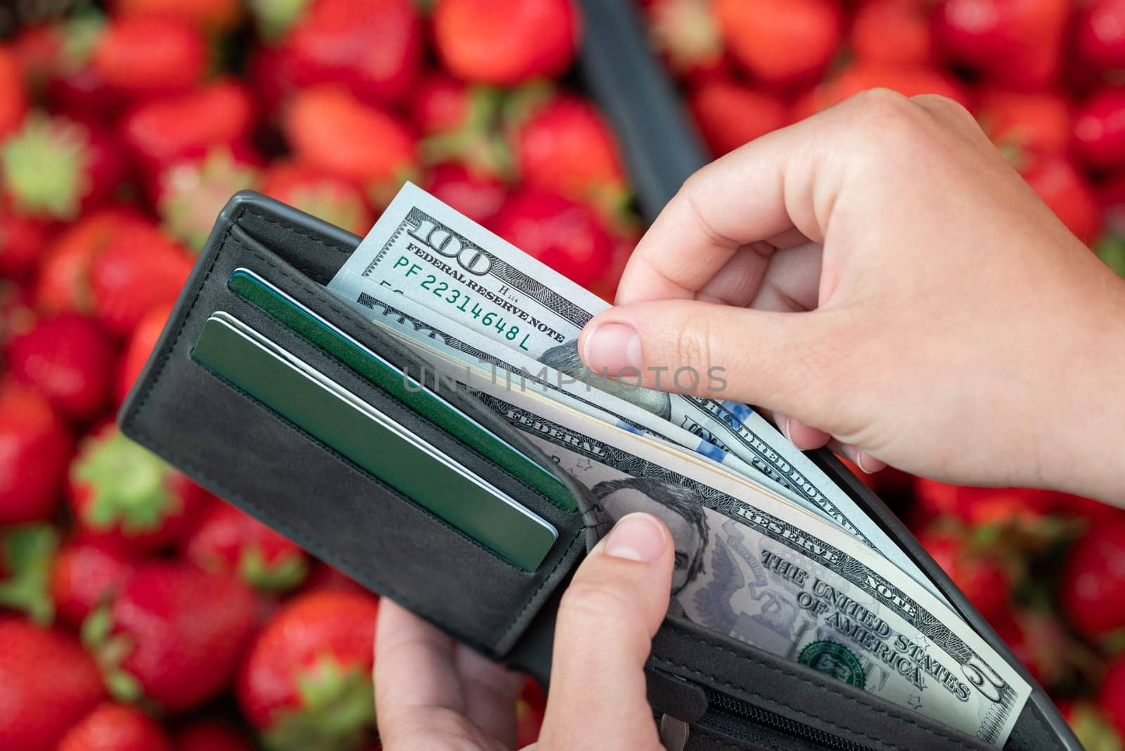 Girl taking 100 dollar bill from the purse to buy strawberries by VitaliiPetrushenko