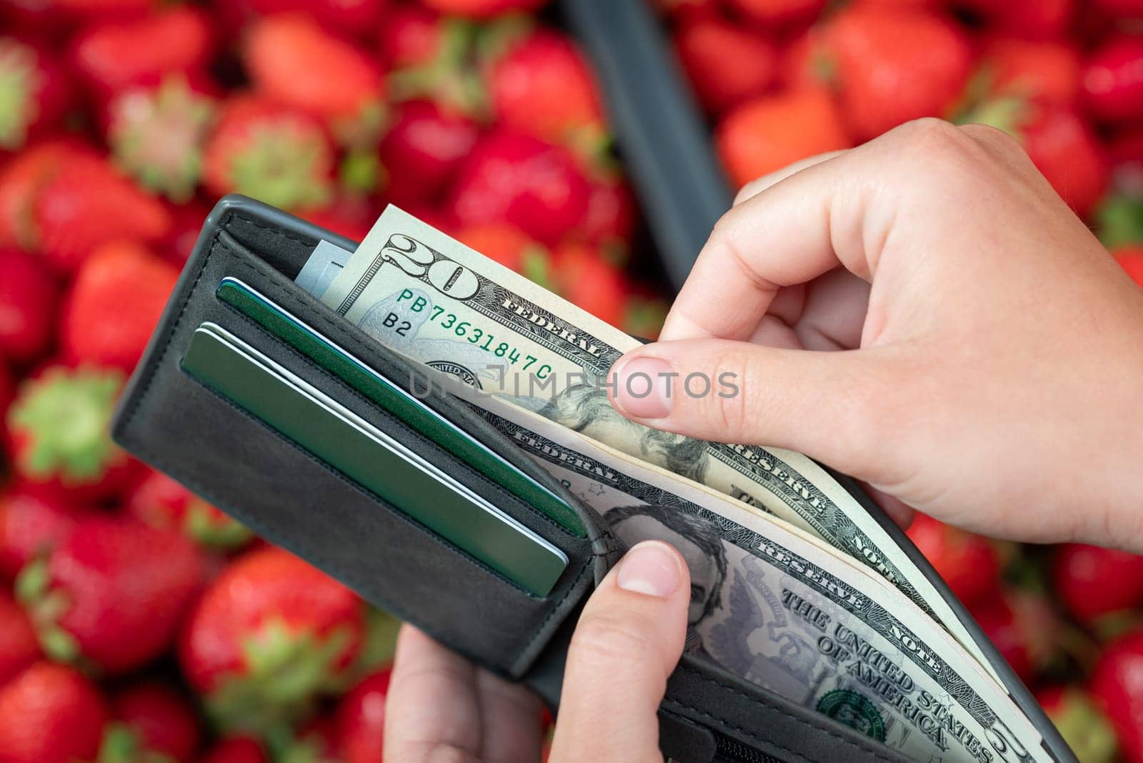 Girl taking 20 dollar bill from the wallet to buy some strawberries by VitaliiPetrushenko