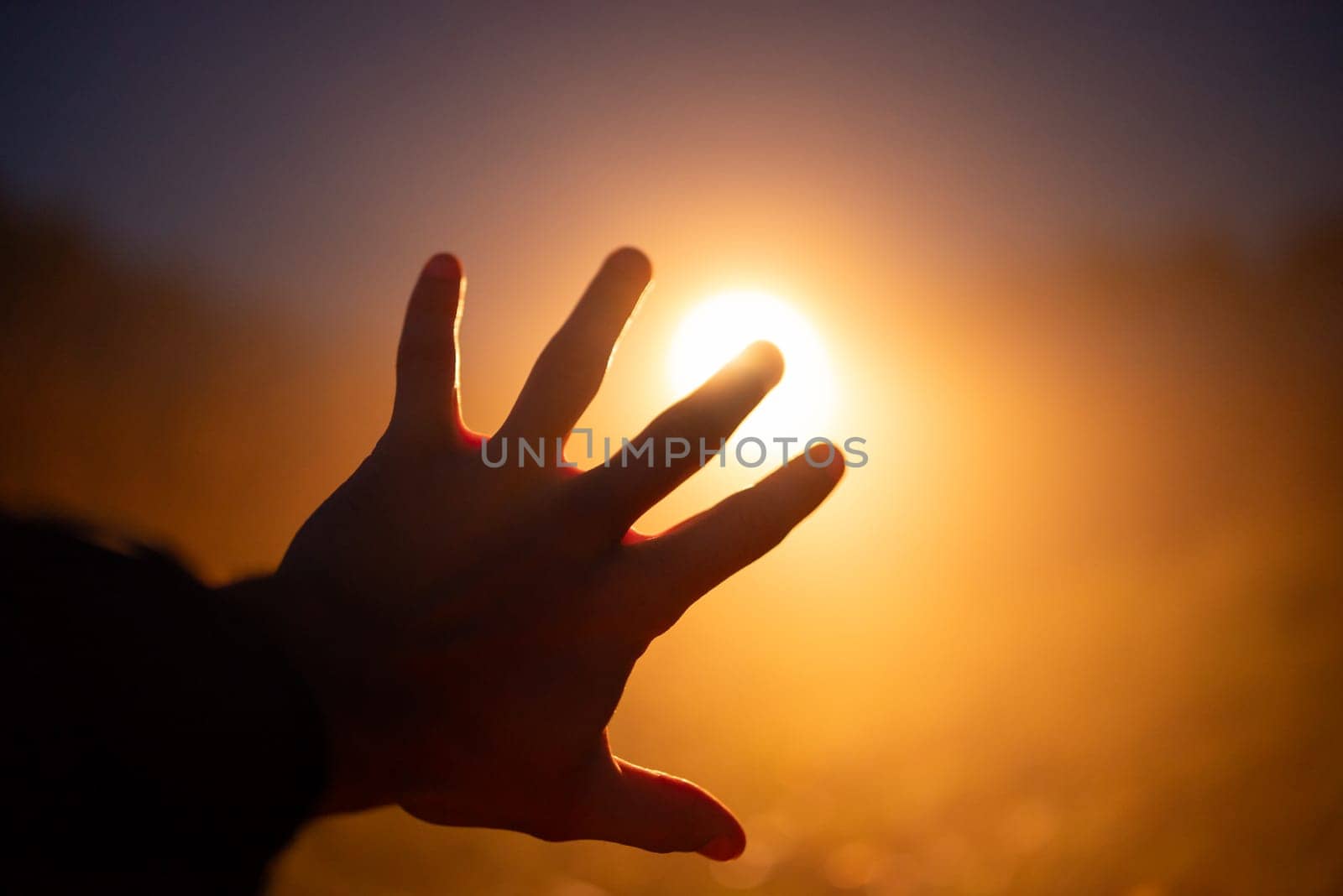 Hand of a person on the background of bright orange vehicle headlight by VitaliiPetrushenko
